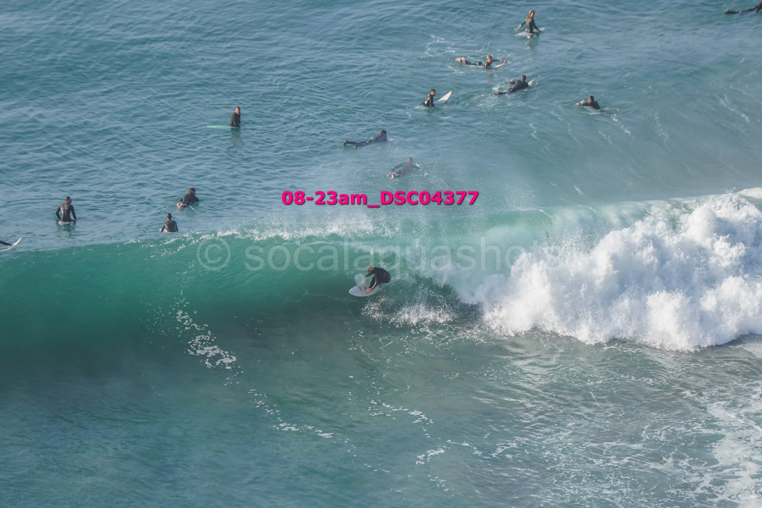 Surfer riding a wave with many people in the water watching from behind