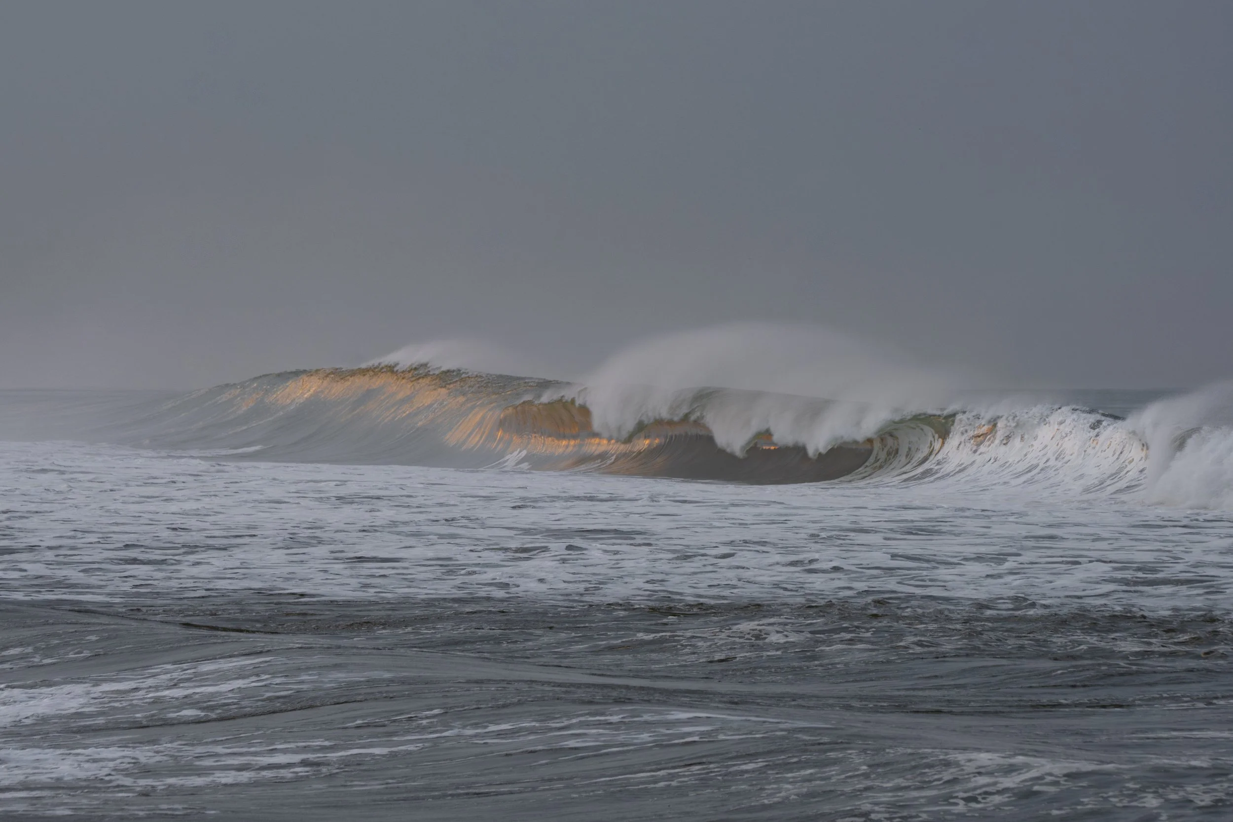 Large ocean waves cresting with white foam under a dark, cloudy sky