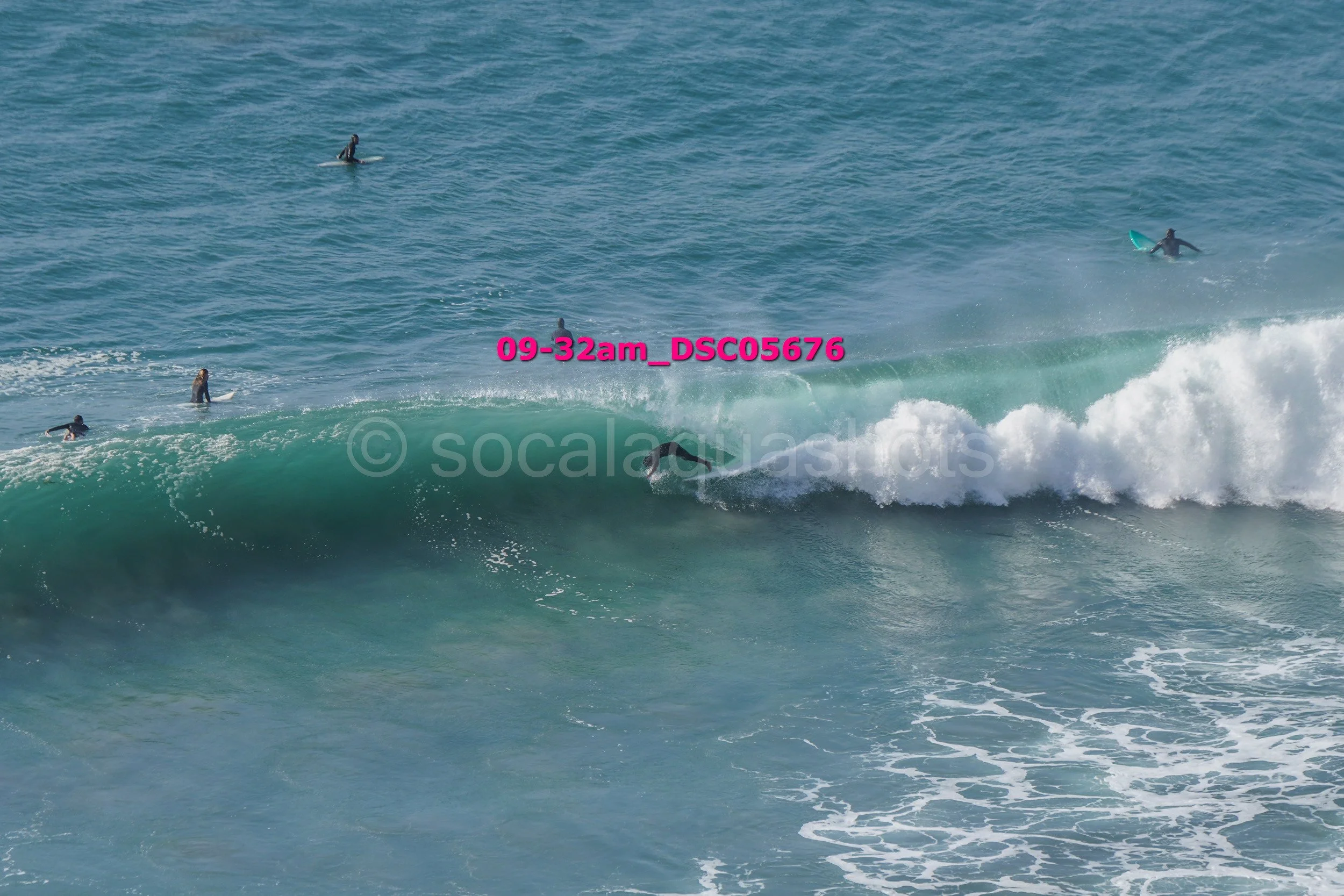 Surfer riding a wave with several other surfers in the water nearby at the beach.