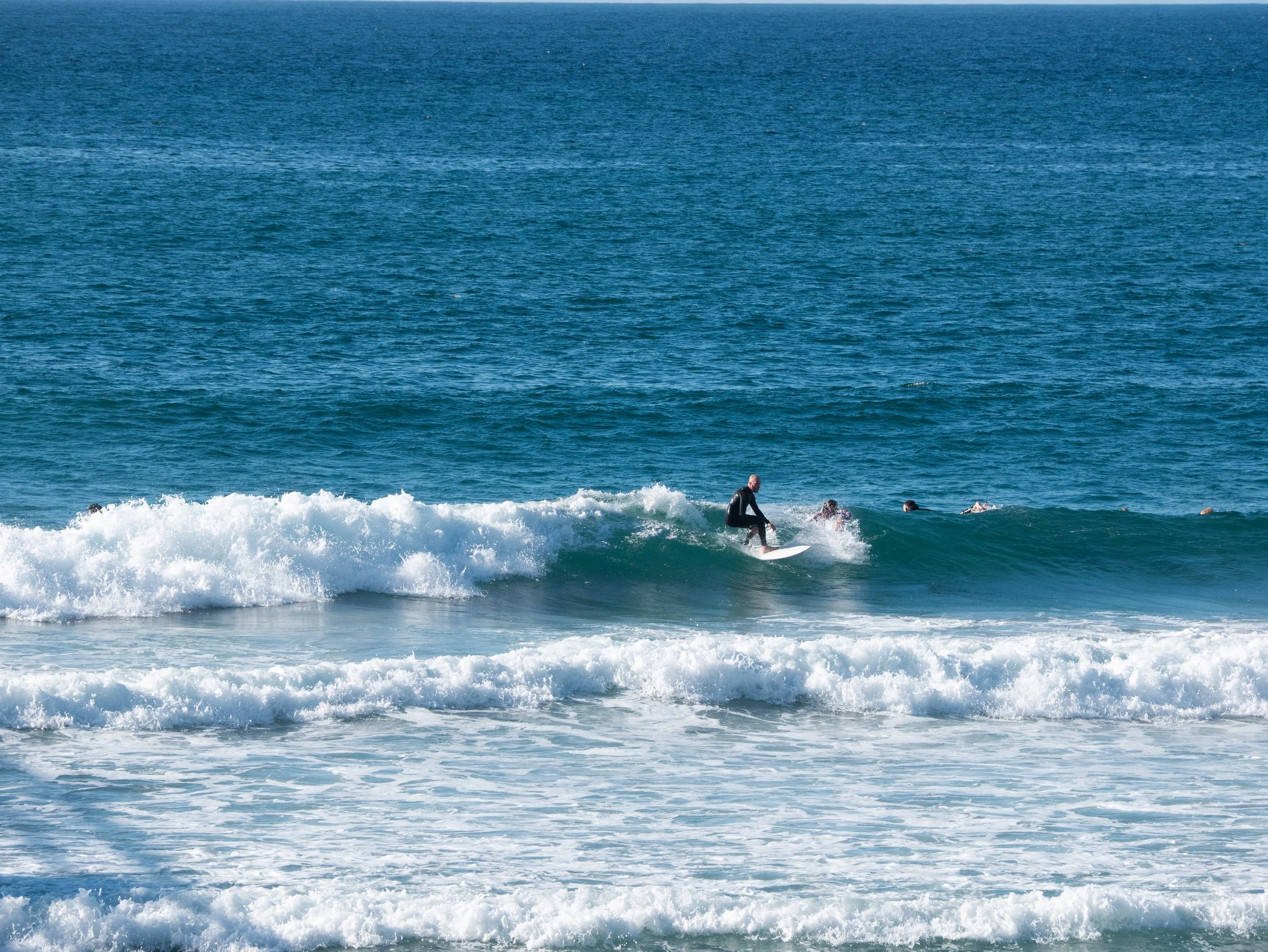 A person surfing on a wave in the ocean with several other surfers nearby.