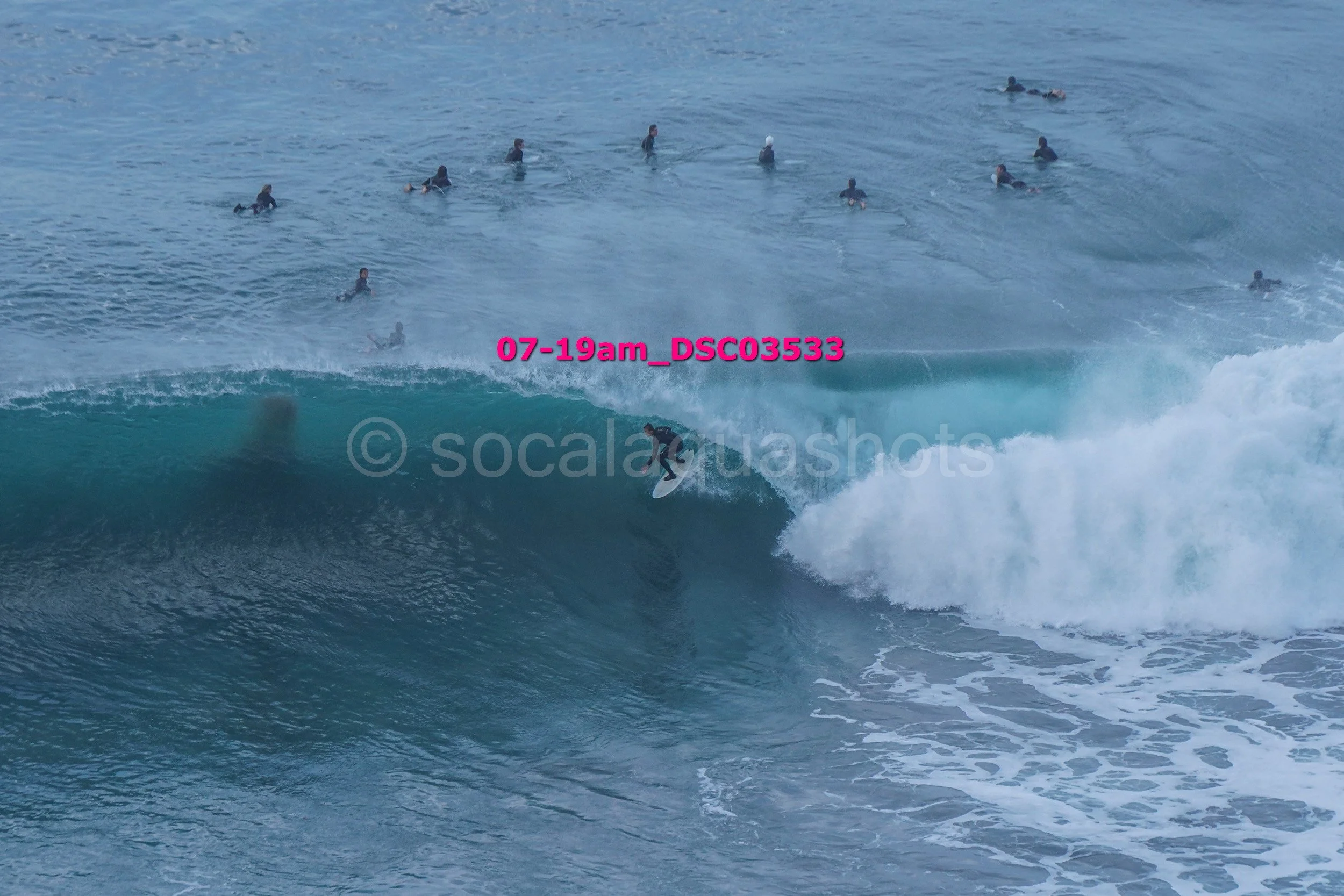 Surfer riding a large wave with multiple surfers in the water in the background