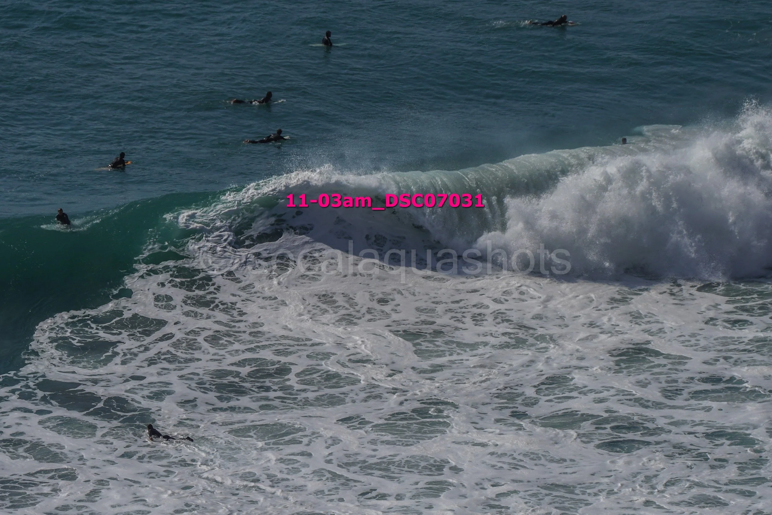 People surfing in the ocean with large waves and foam.