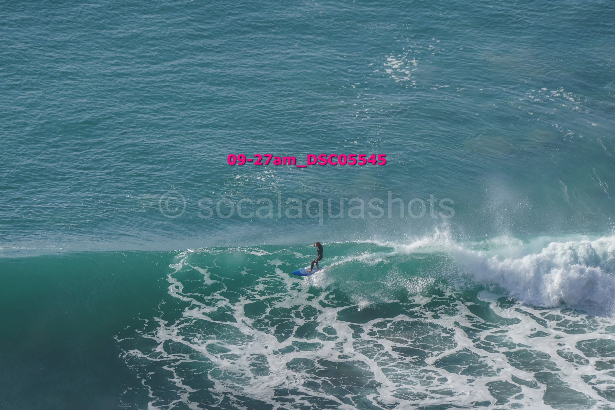 A person surfing on a wave in the ocean on a sunny day.