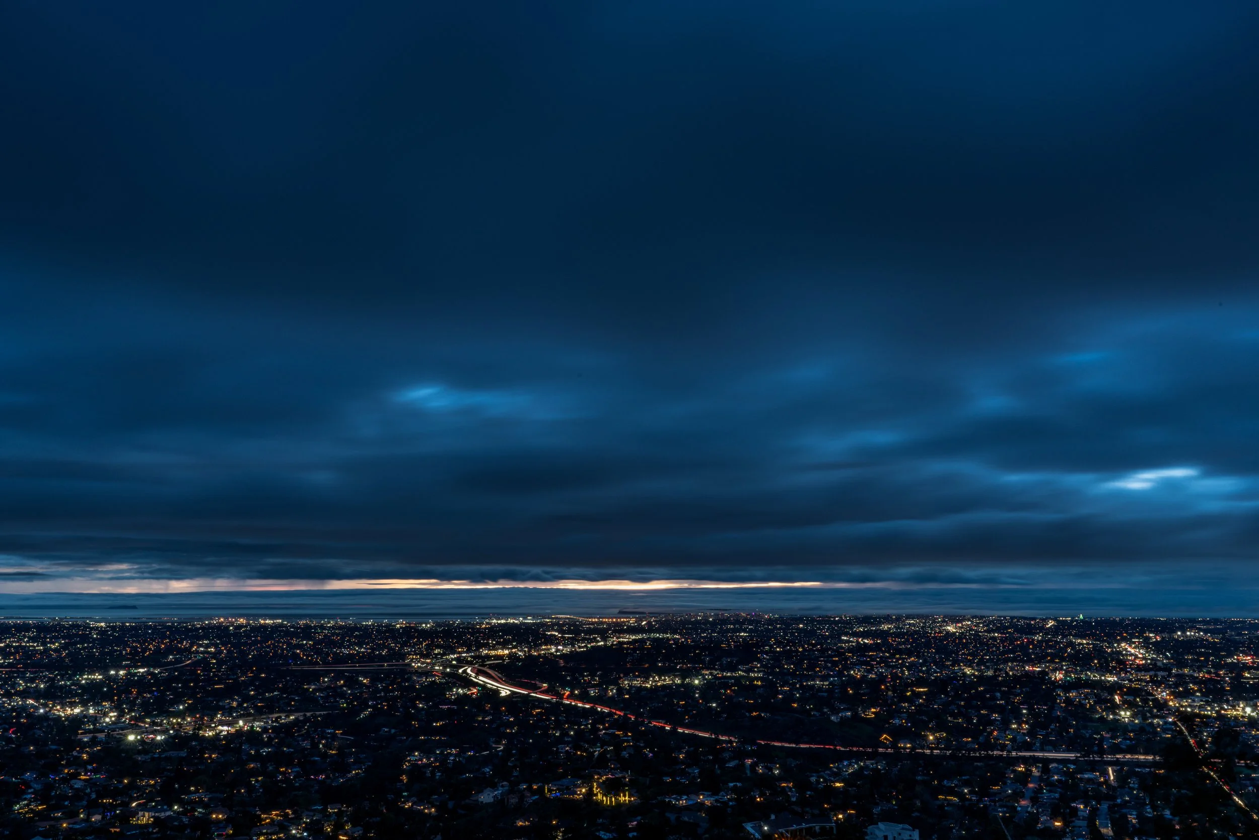 Nighttime cityscape with a cloudy sky and city lights visible below.