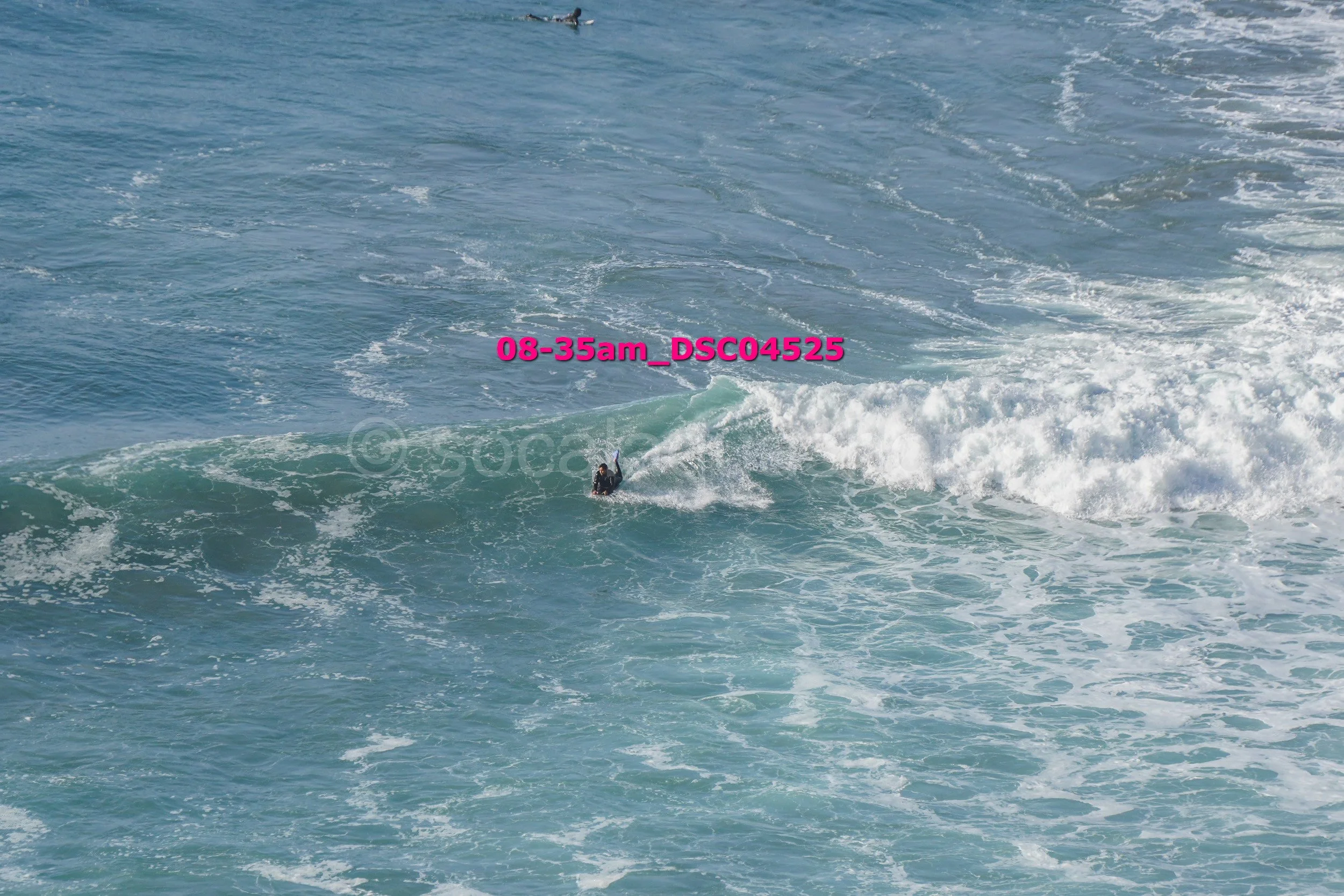 A surfer riding a wave in the ocean on a sunny day.