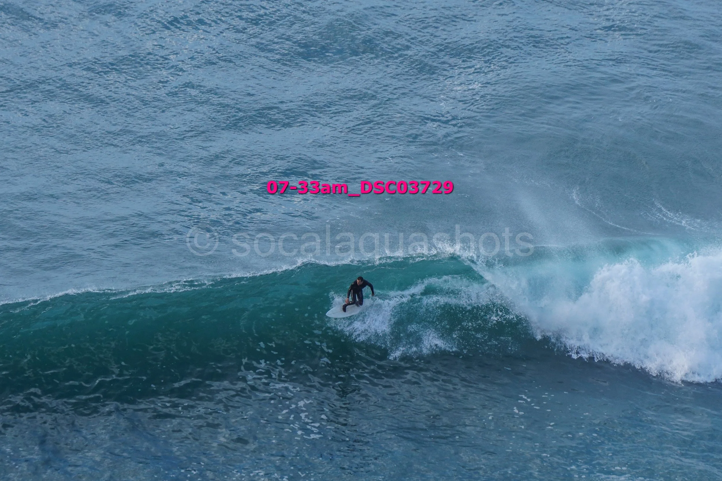 A surfer in a black wetsuit riding a wave in the ocean during daytime.