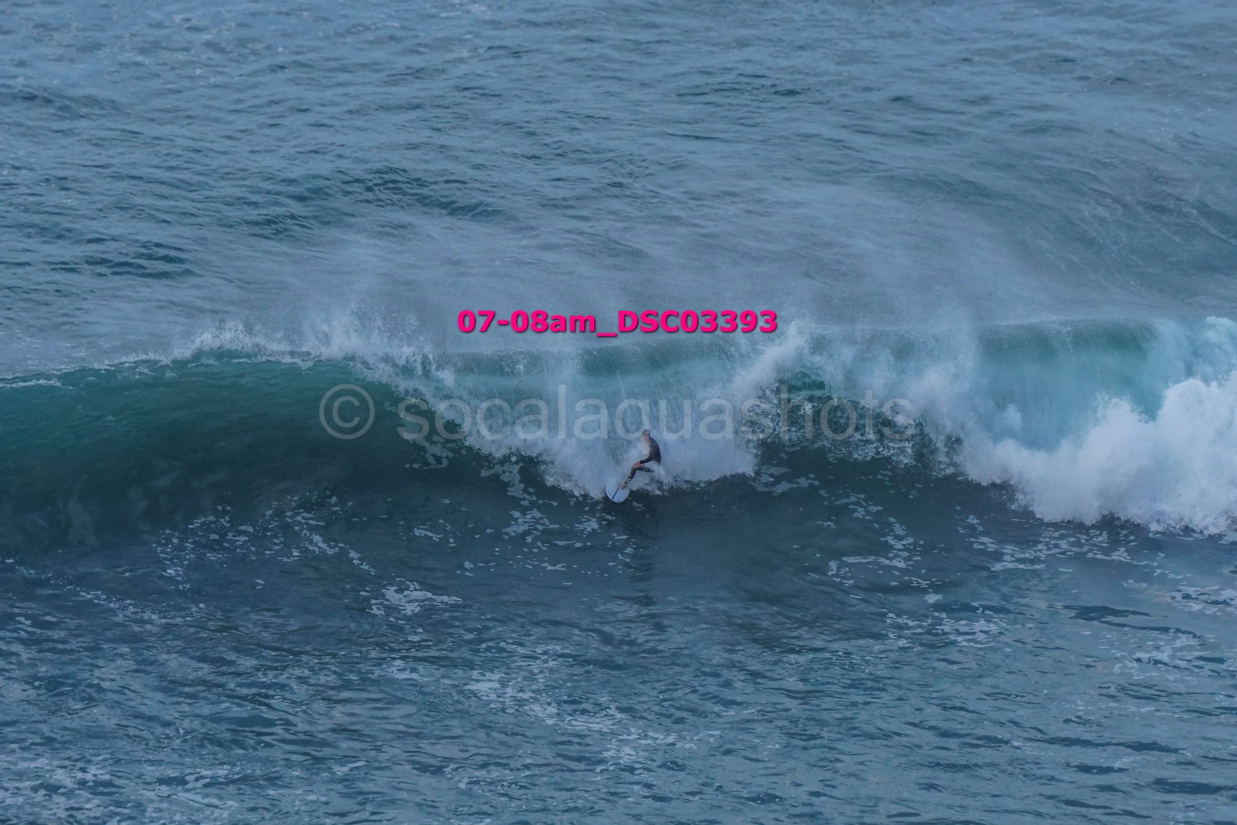 A person surfing on a large ocean wave with spray and foam.