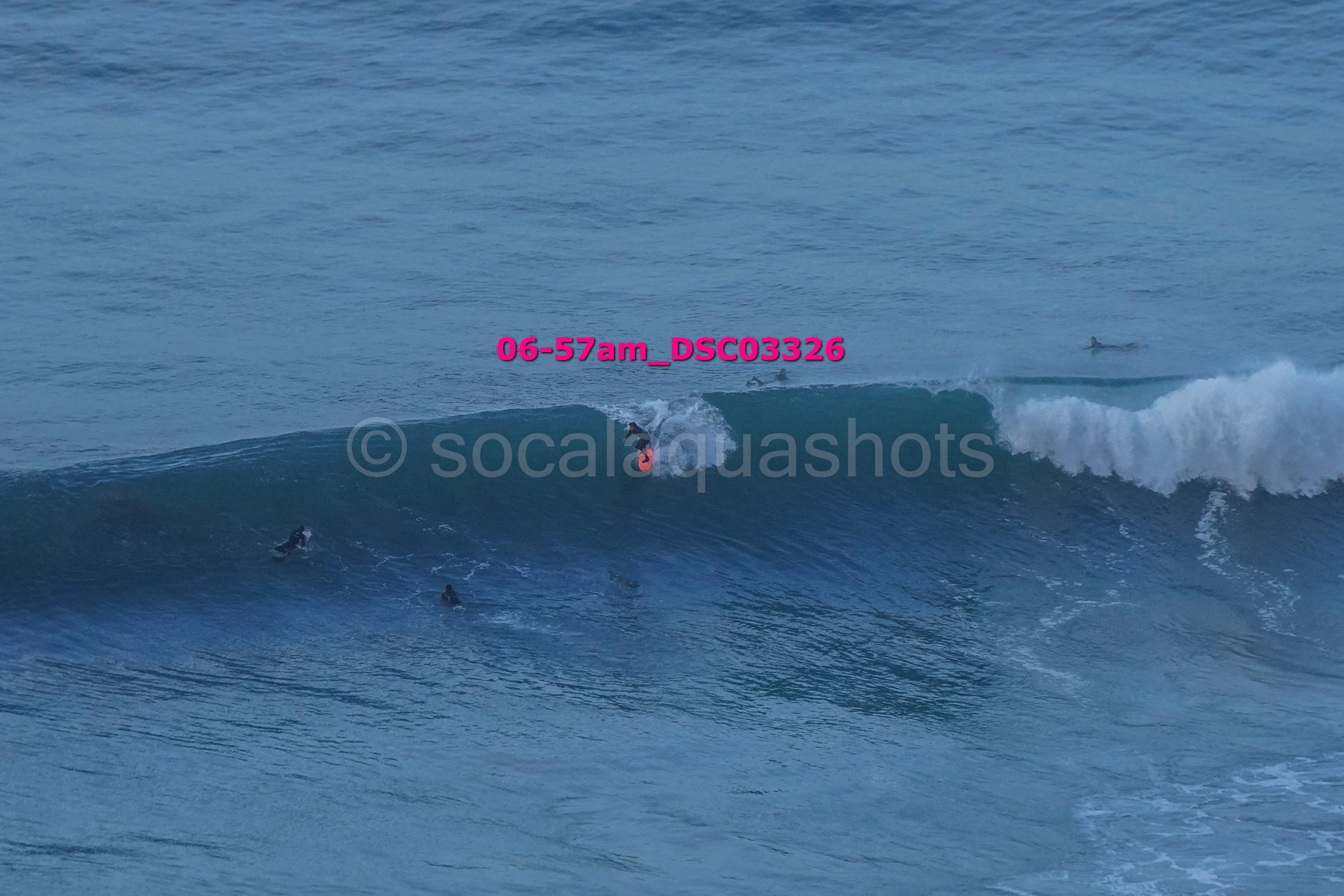 Surfer riding a wave with several other surfers in the water and the ocean in the background.
