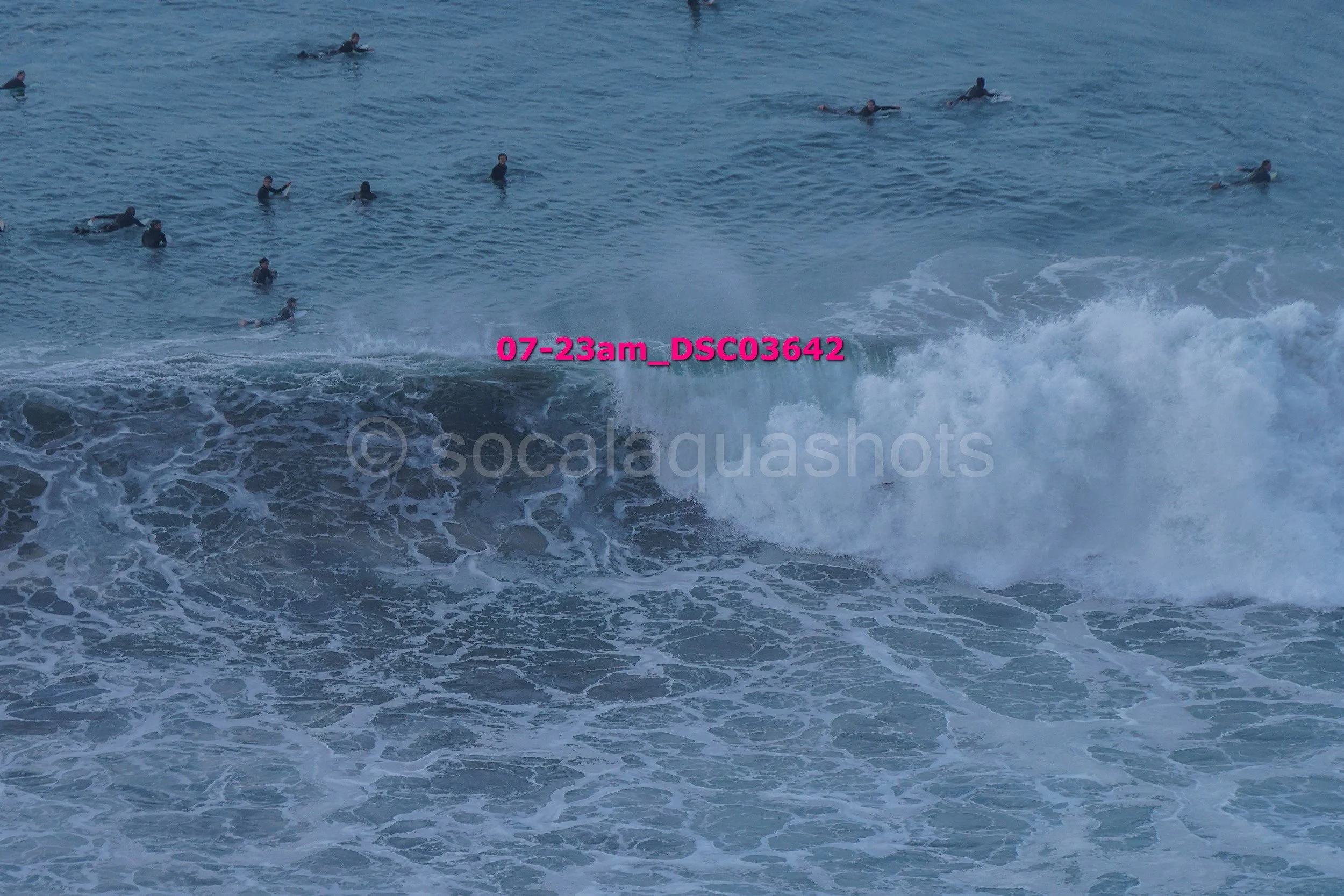A group of people swimming and surfing in the ocean with waves.