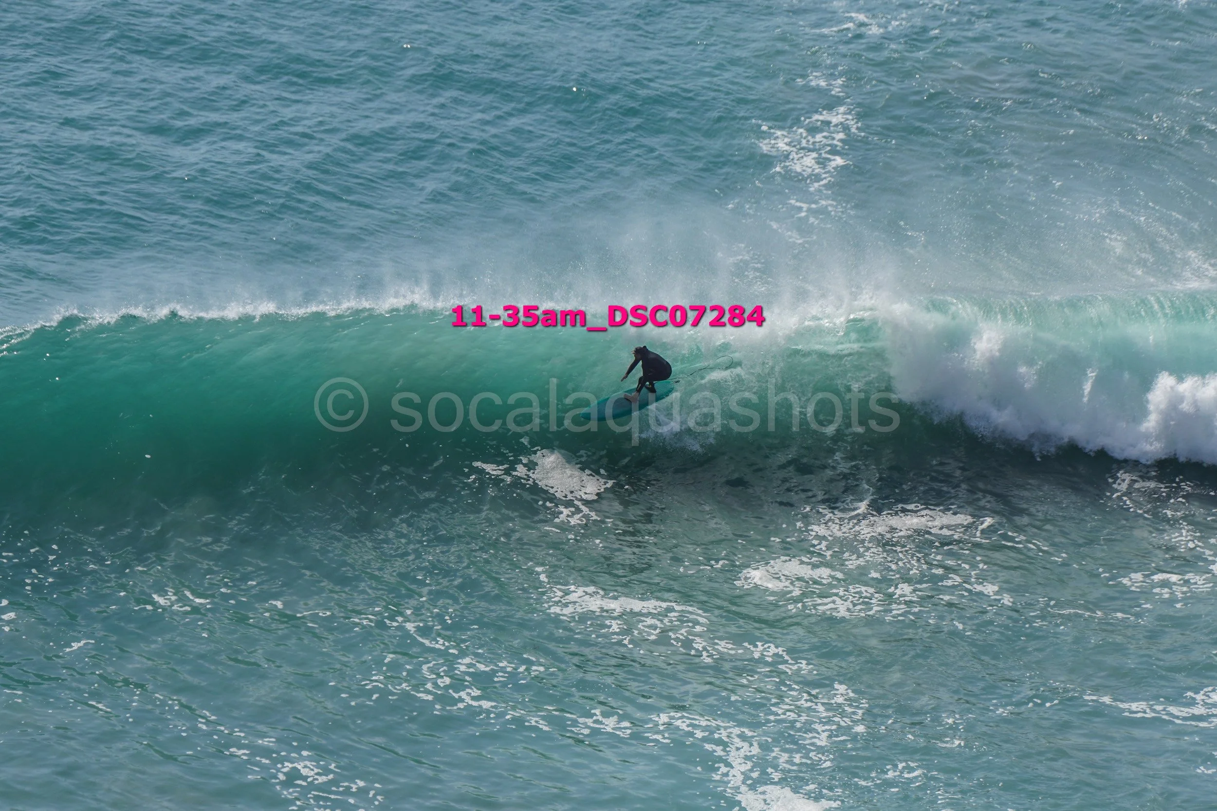 A person surfing on a large wave in the ocean, wearing a wetsuit.