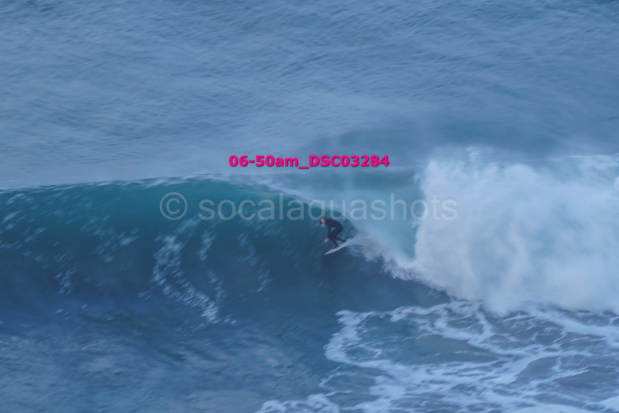 A person surfing on a large wave in the ocean during daylight.
