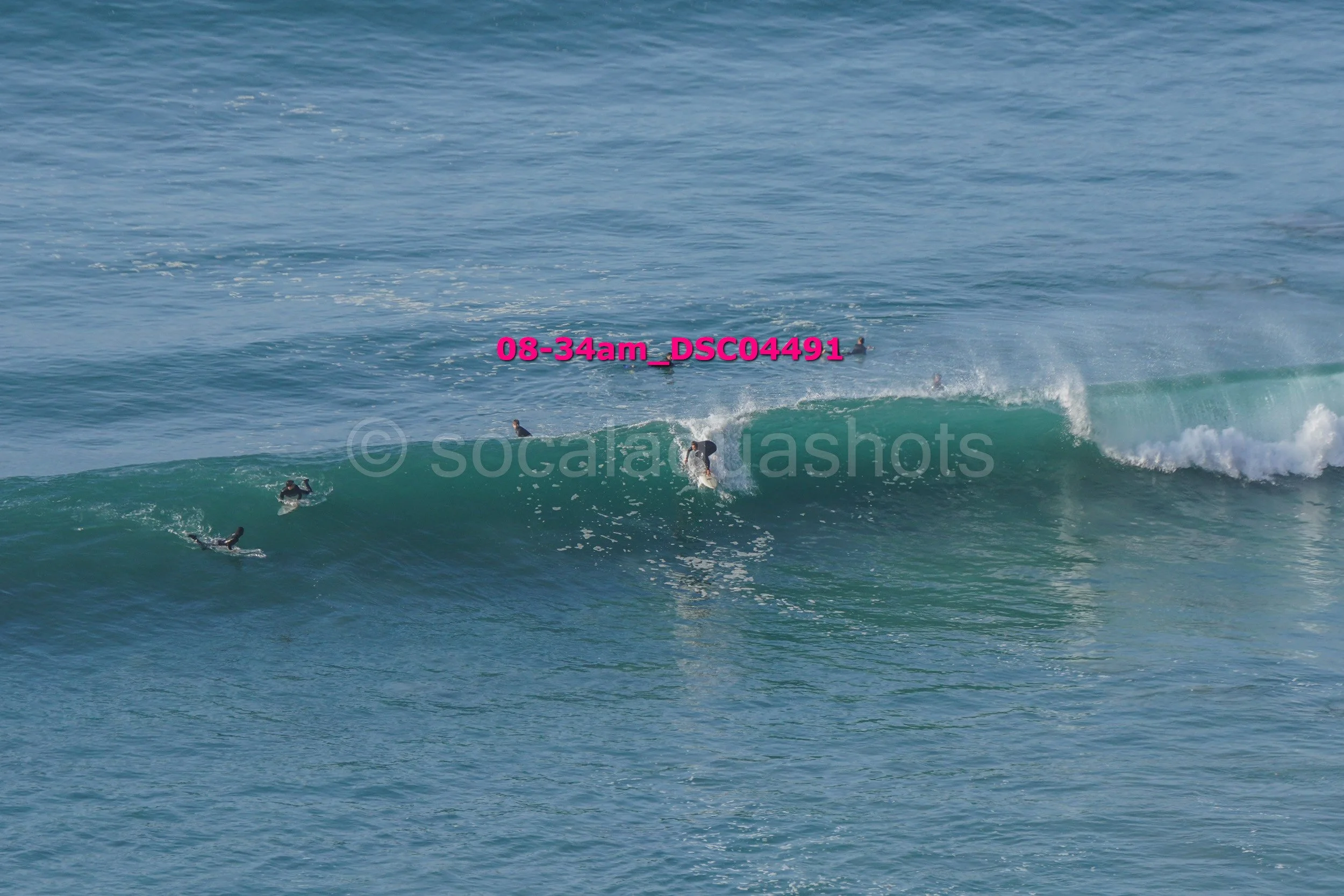 Multiple surfers riding a large ocean wave near the shoreline.