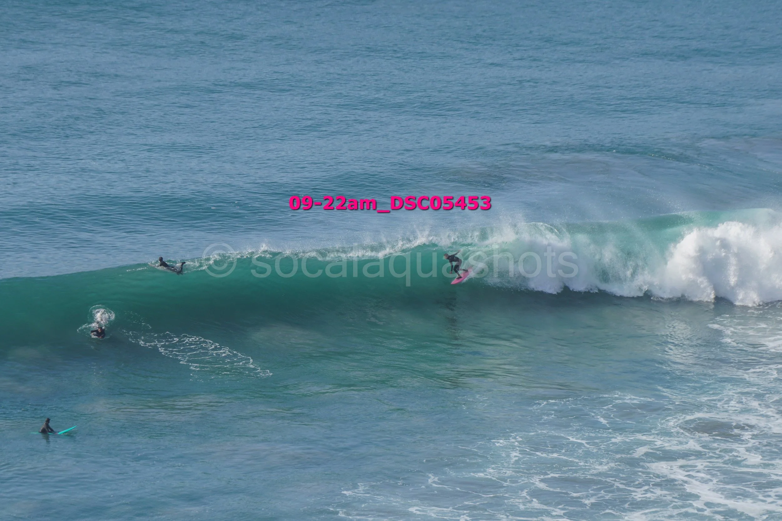 Surfer riding a wave with other surfers in the water during daytime.