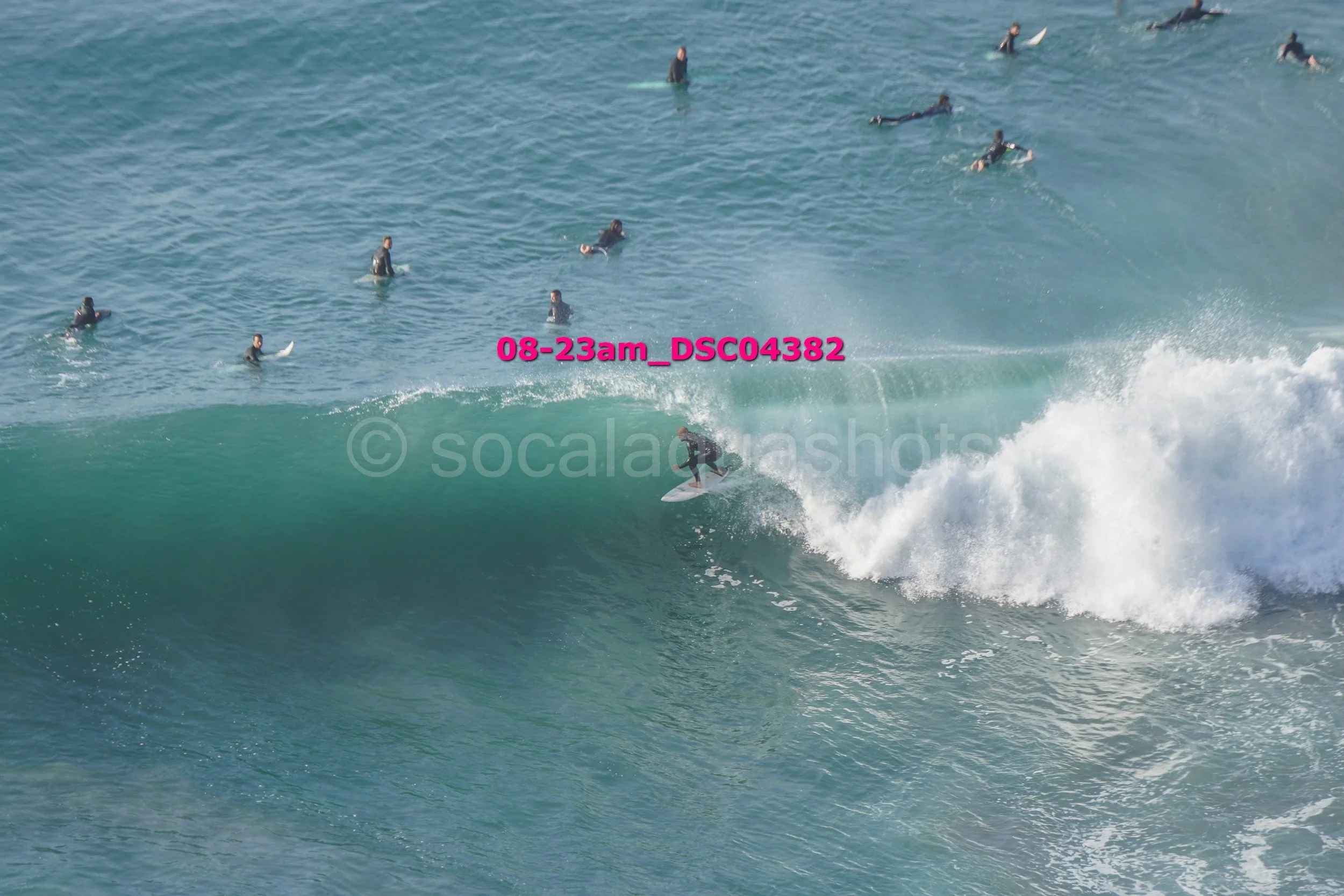 Surfer riding a wave with multiple surfers in the background in the ocean.