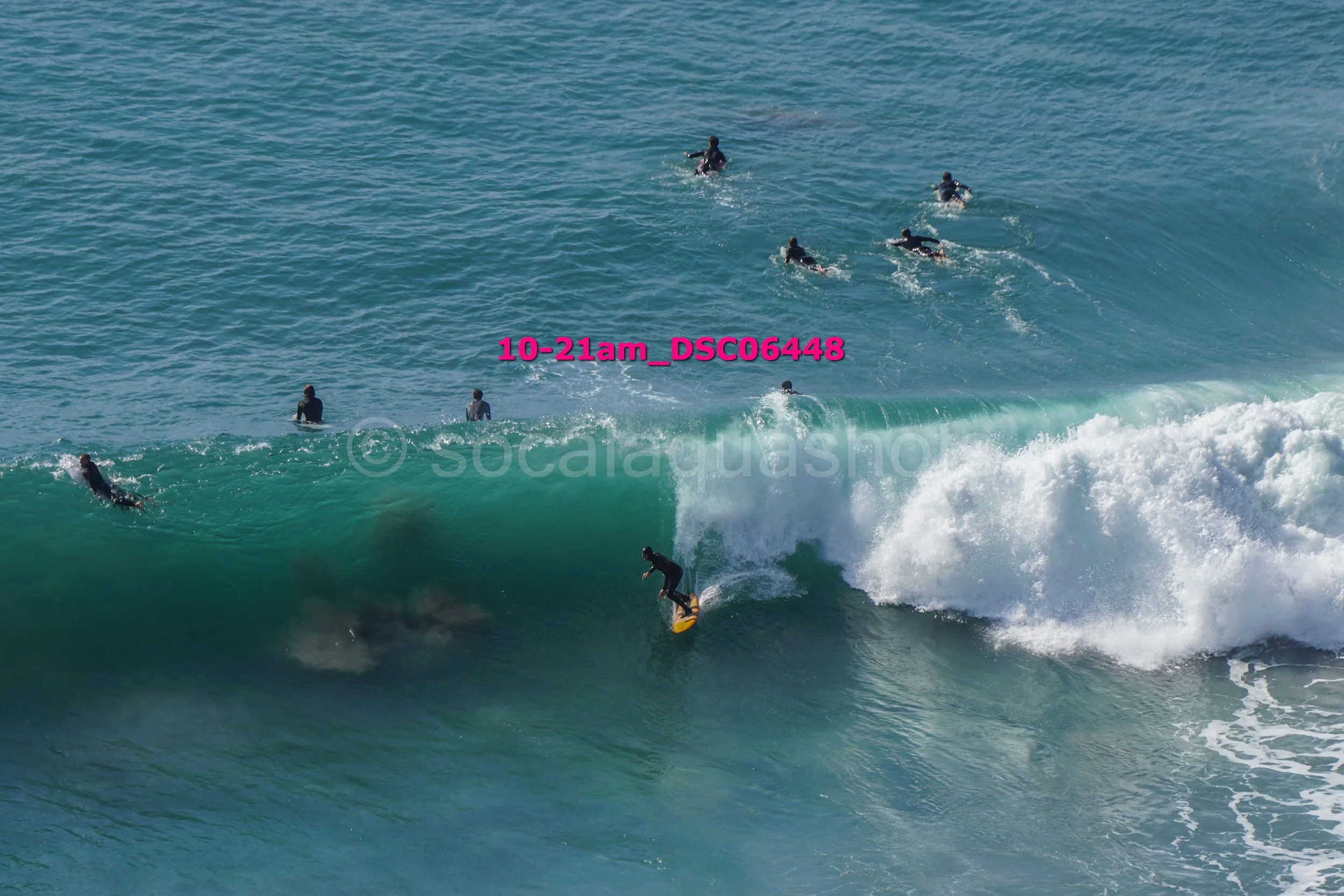 Surfer riding a wave with multiple surfers in the background in the ocean.