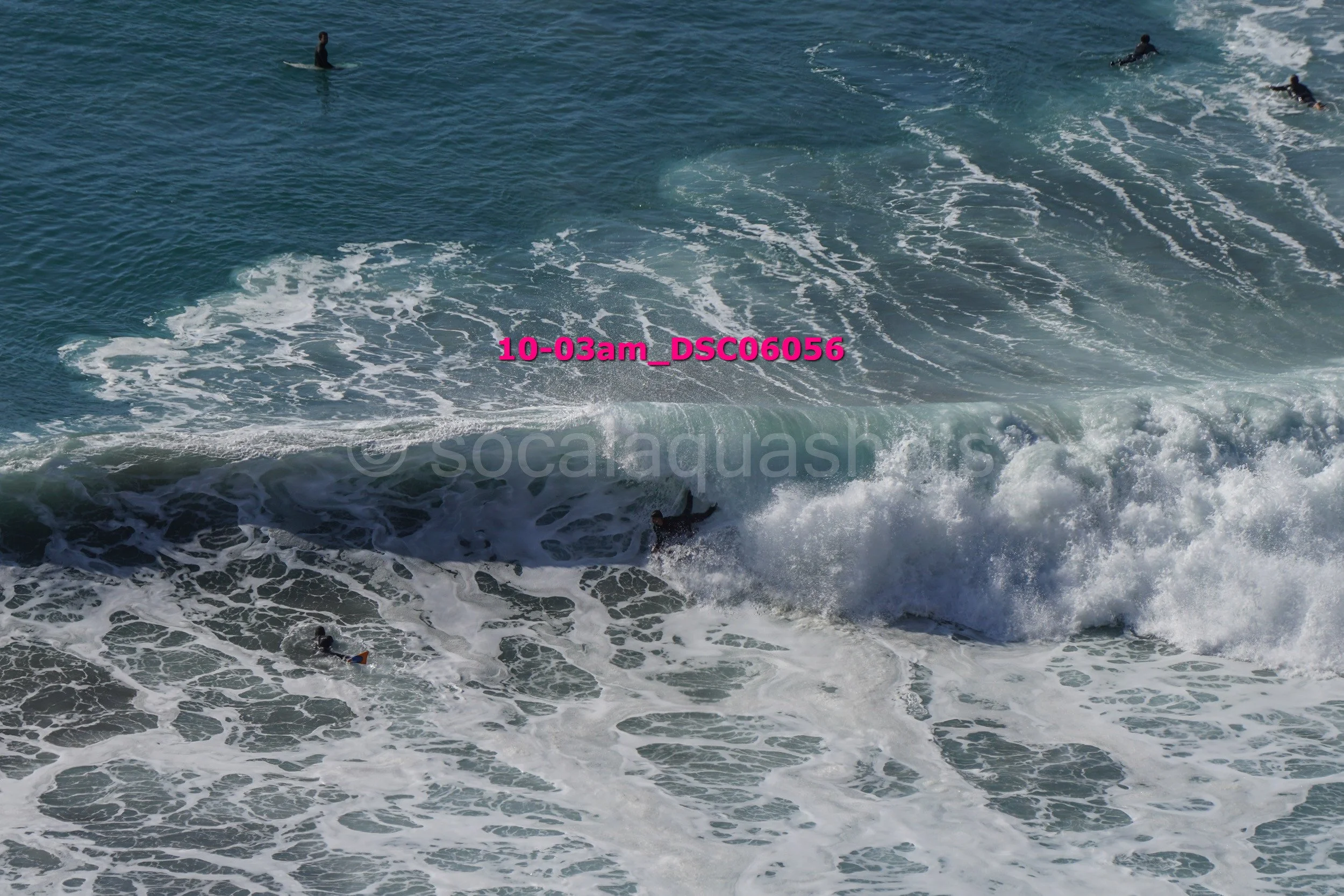 Surfers in the ocean riding waves and waiting for waves in the water.