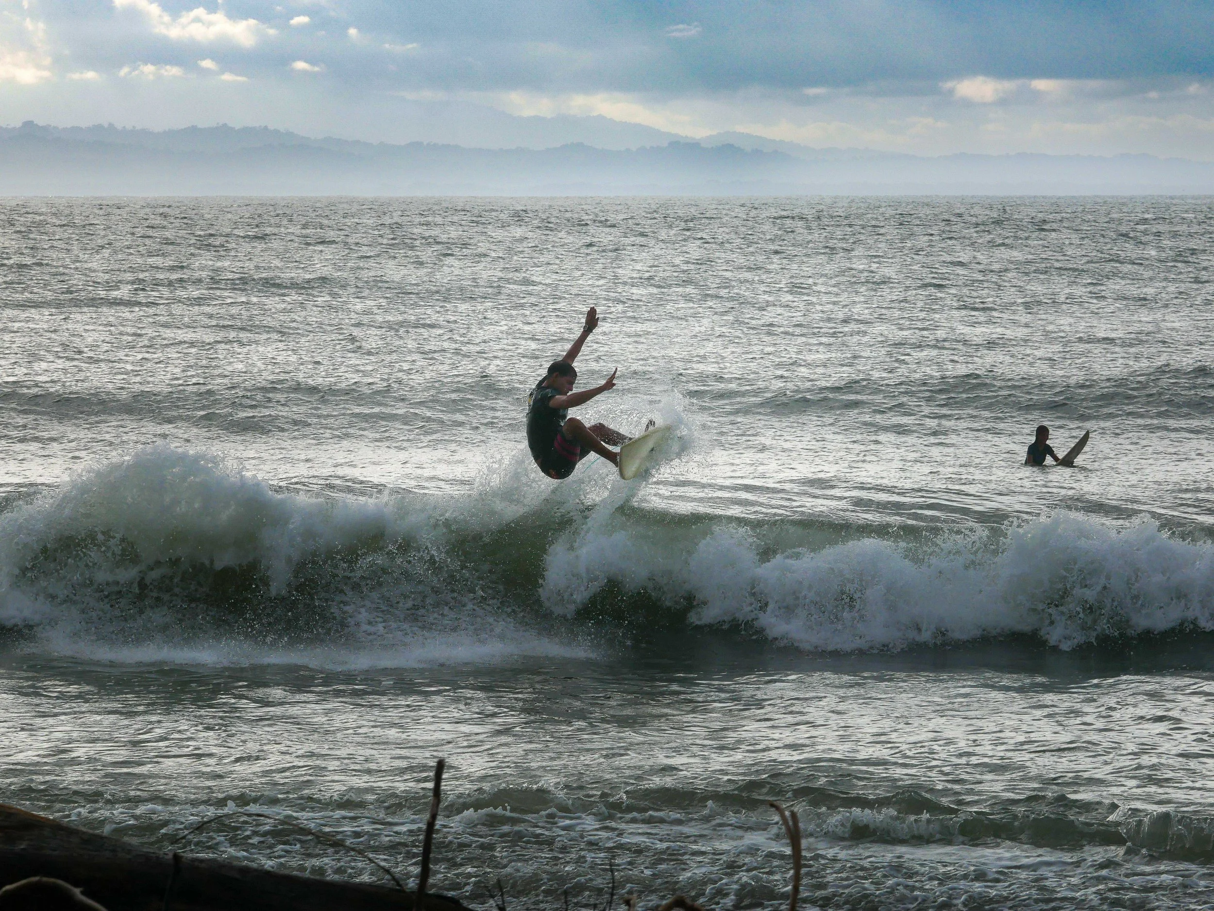 Surfer doing a trick on a wave, ocean background, another person in water