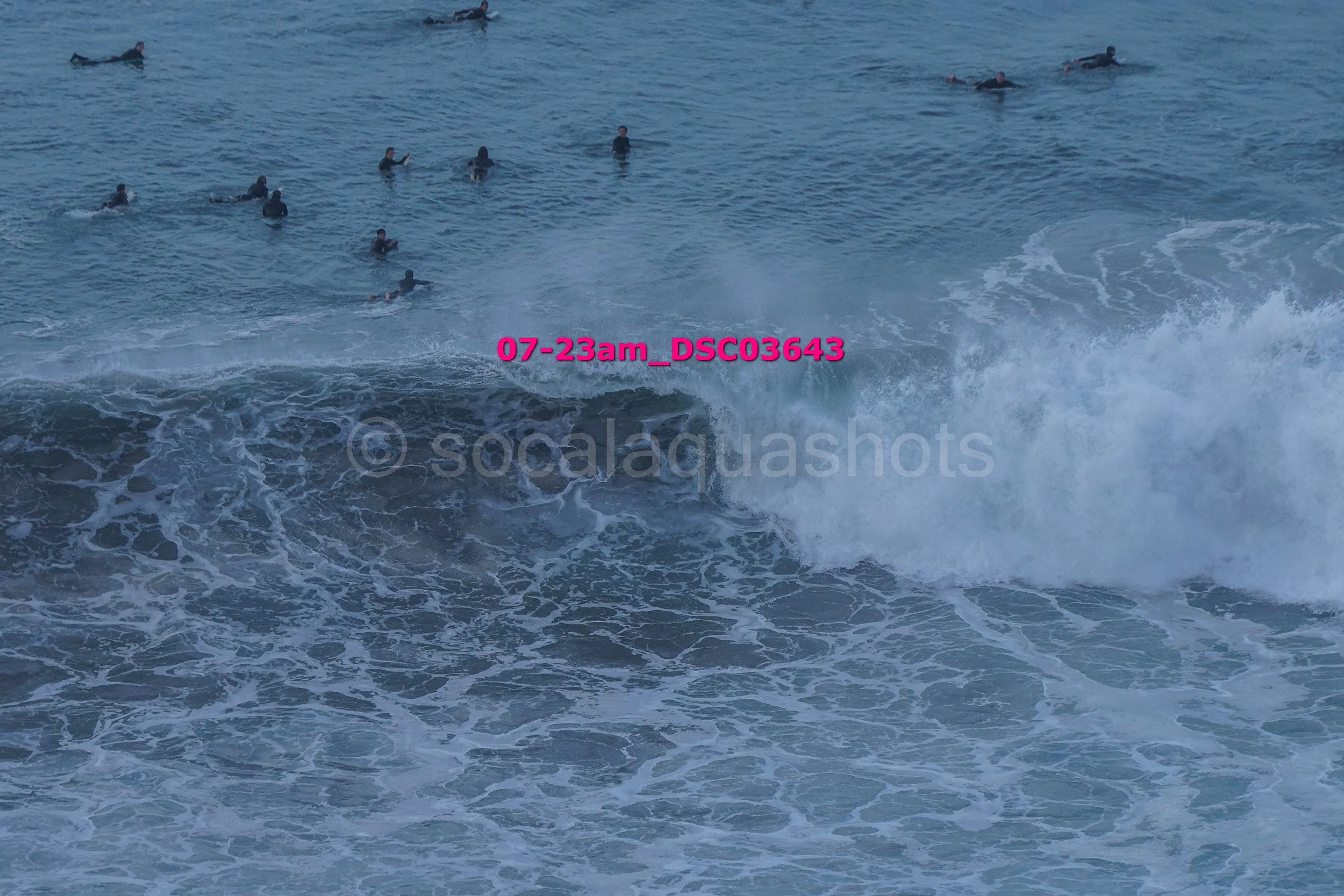 A group of people swimming in the ocean near the shore with waves crashing