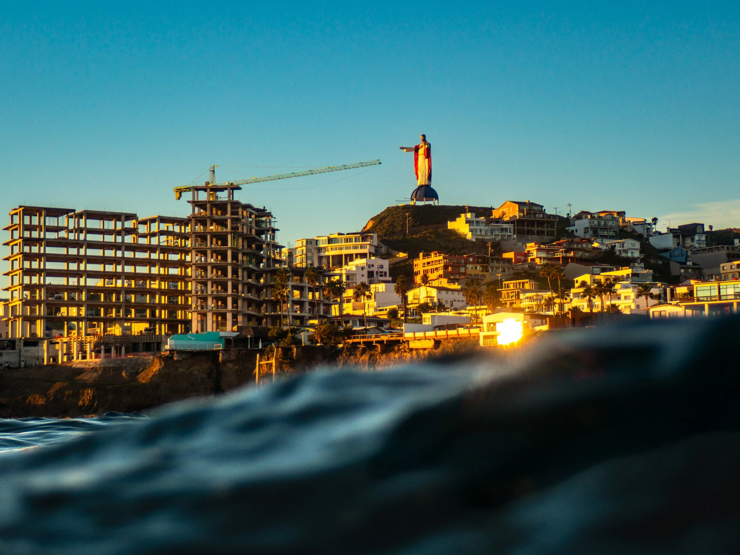 Scenic view of beachfront city with a Macys parade balloon in the distance, taken from the water at sunset.