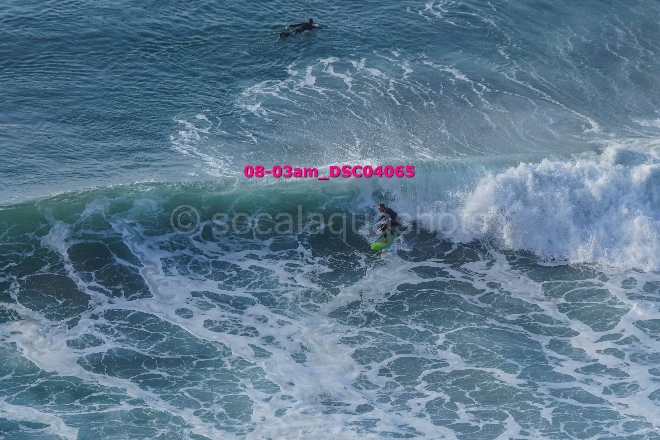 A person in a black wetsuit riding a yellow surfboard on a large wave in the ocean.