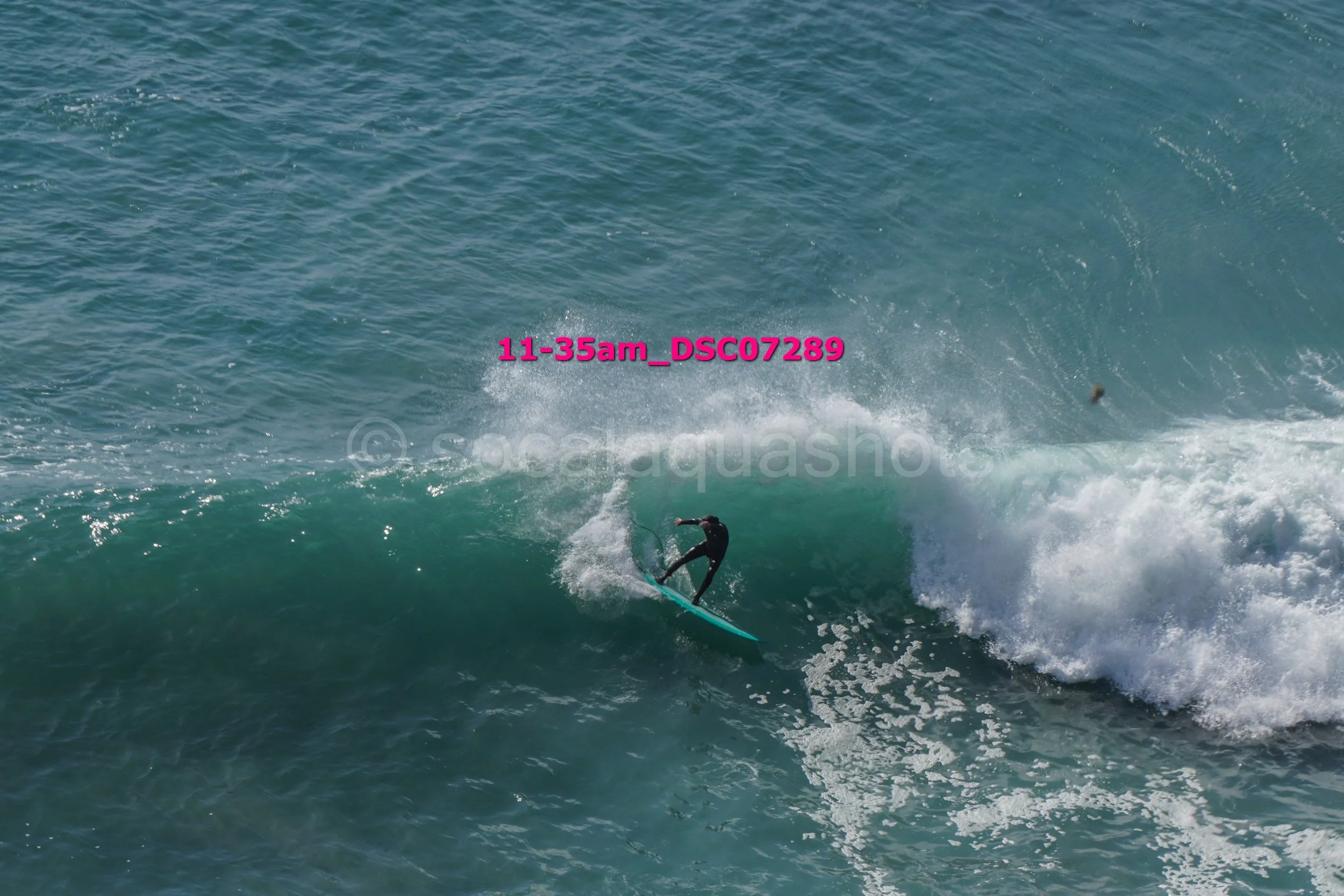 A person surfing on a wave in the ocean, wearing a wetsuit.