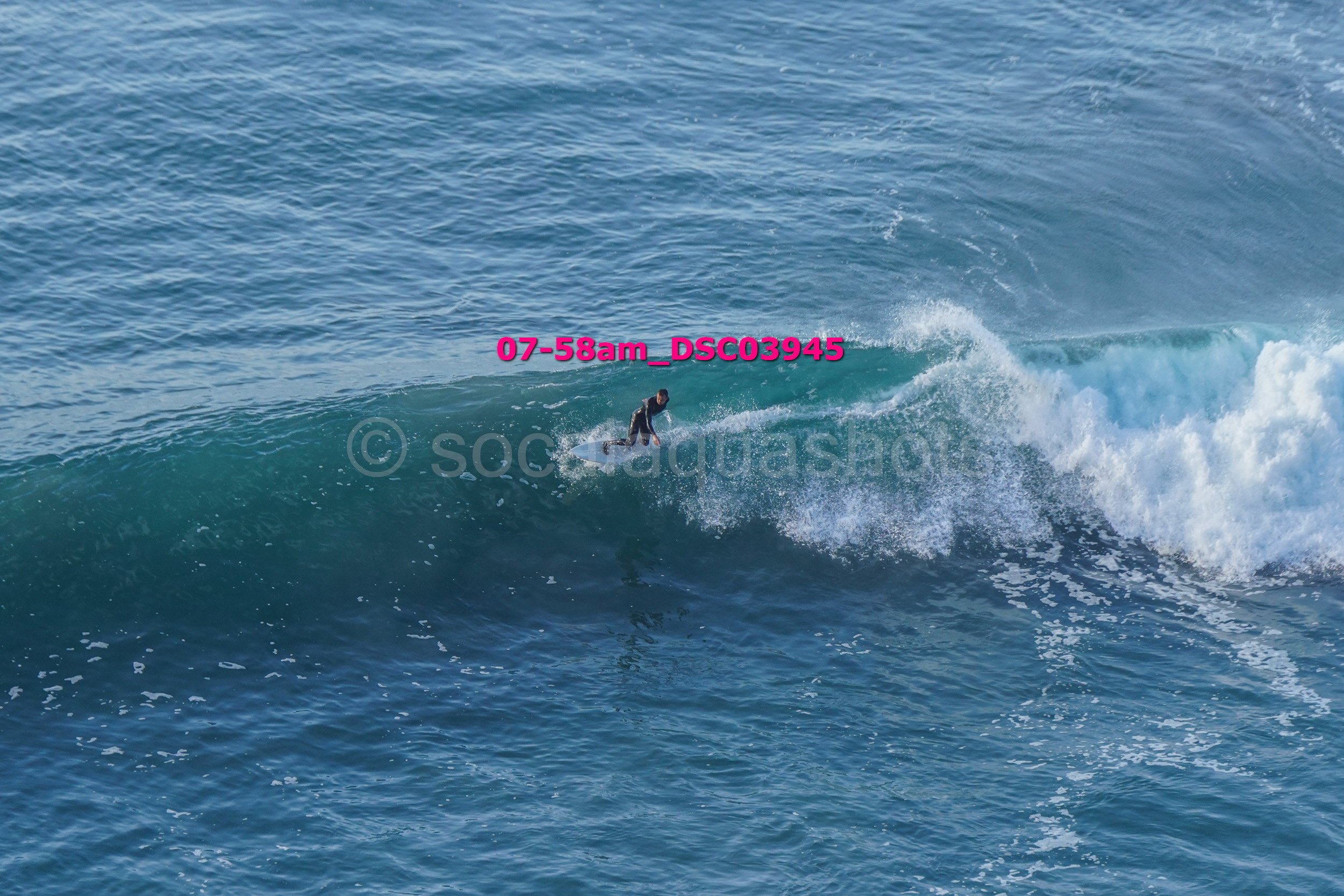 A person surfing on a large ocean wave with water splashing around.