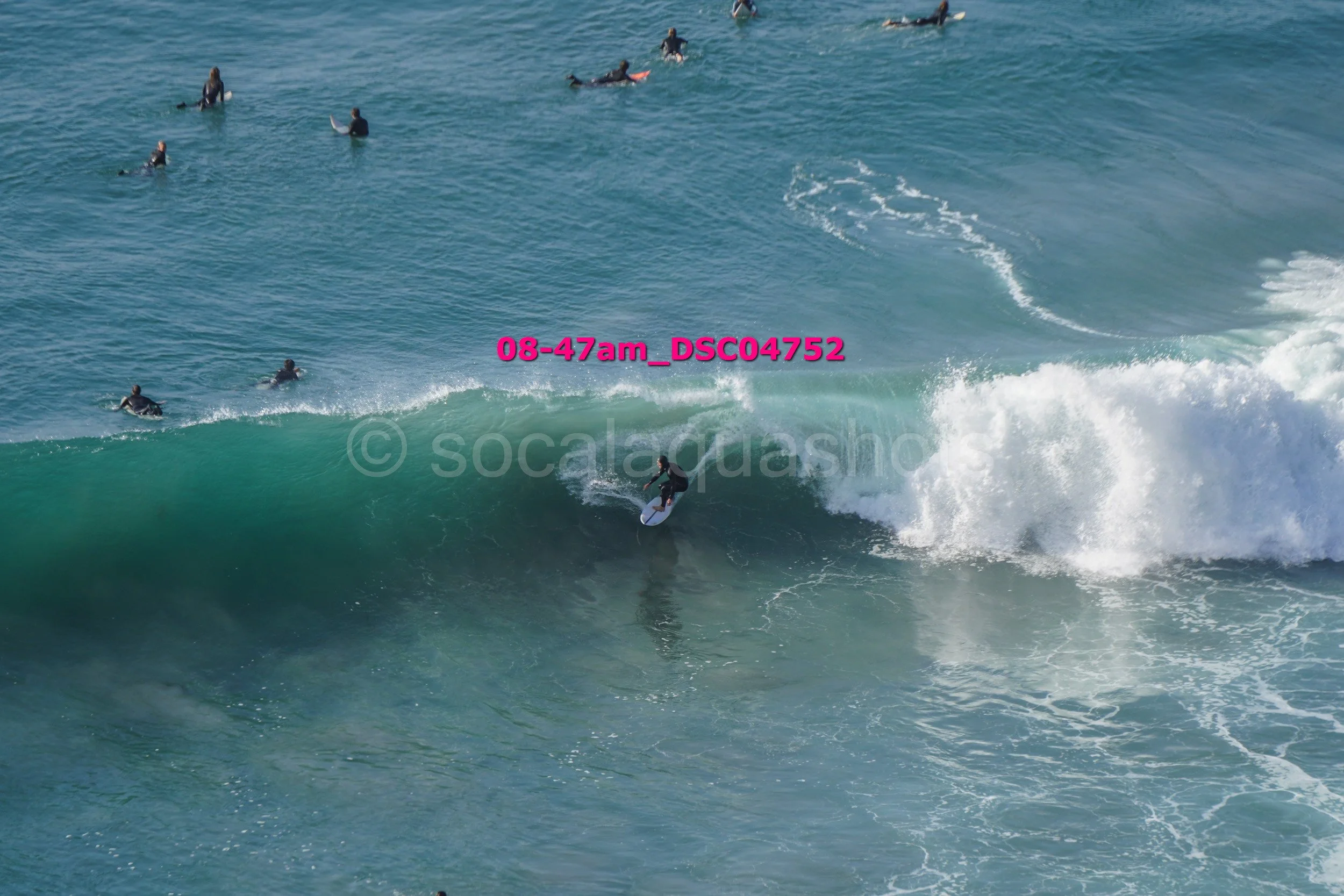 Surfer riding a wave with several surfers in the water around him.