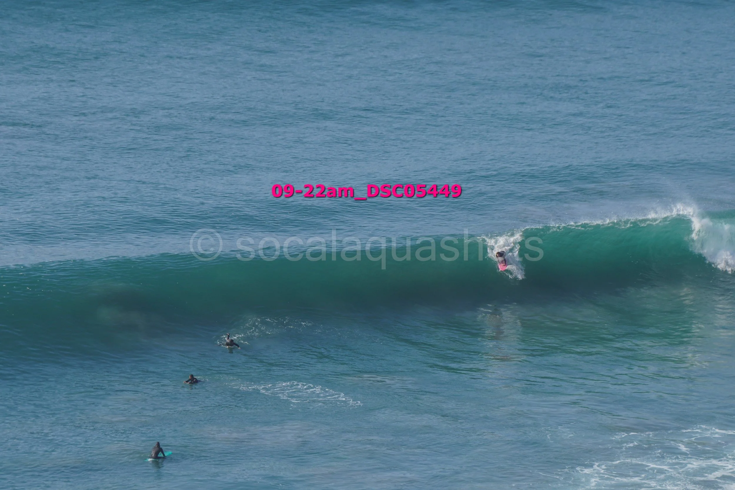 Surfer riding a wave with other surfers in the water nearby during daytime.