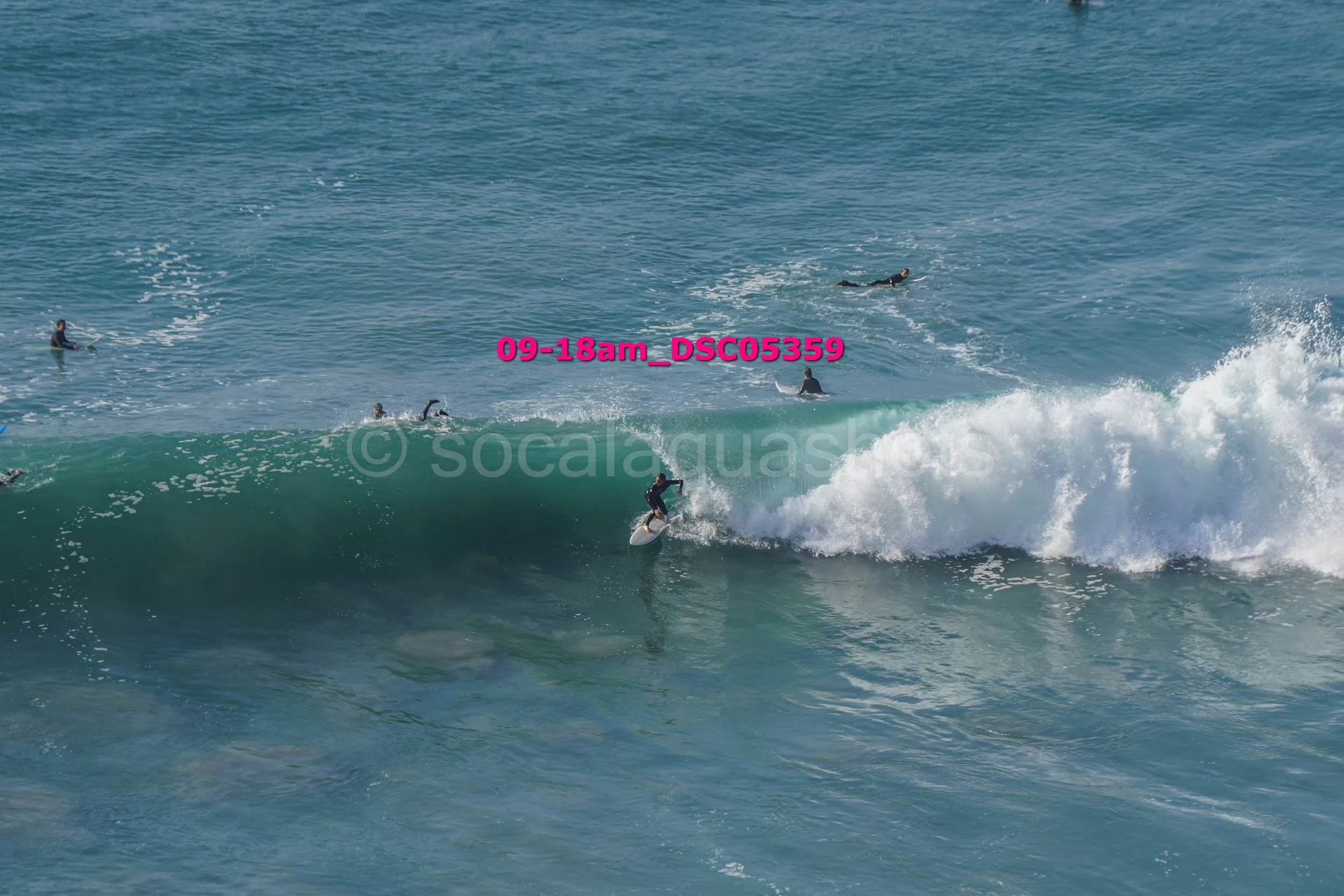 Surfer riding a large wave with multiple surfers in the water in the background