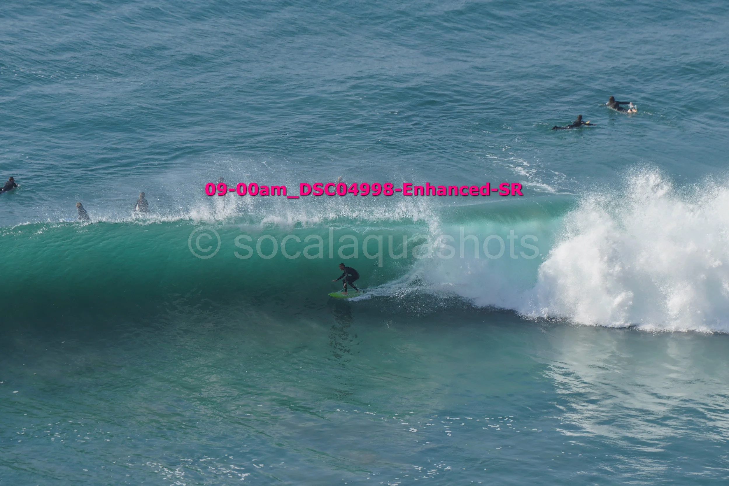 Surfer riding a wave with several surfers in the water in the background.