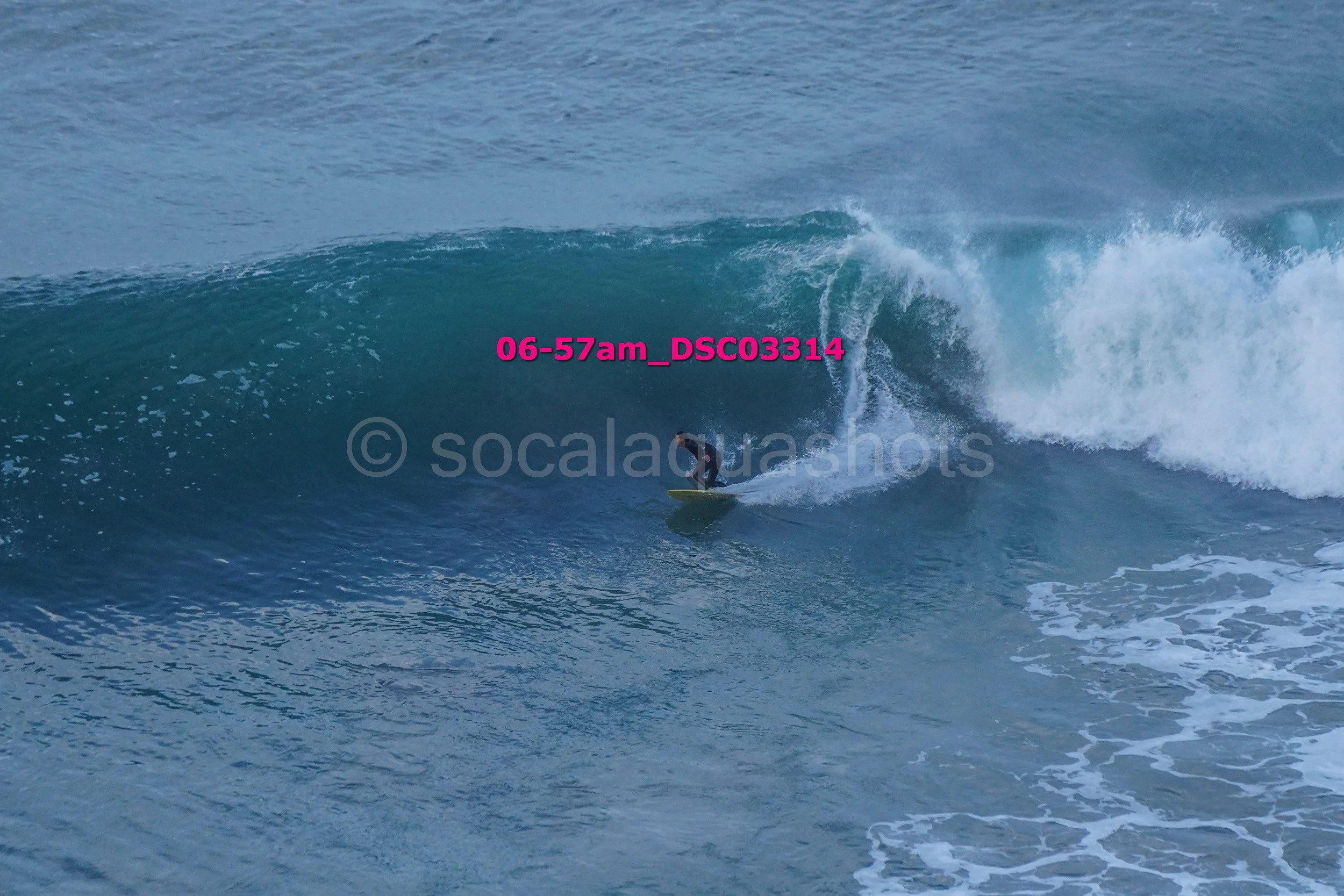 A surfer riding inside the curl of a large ocean wave.