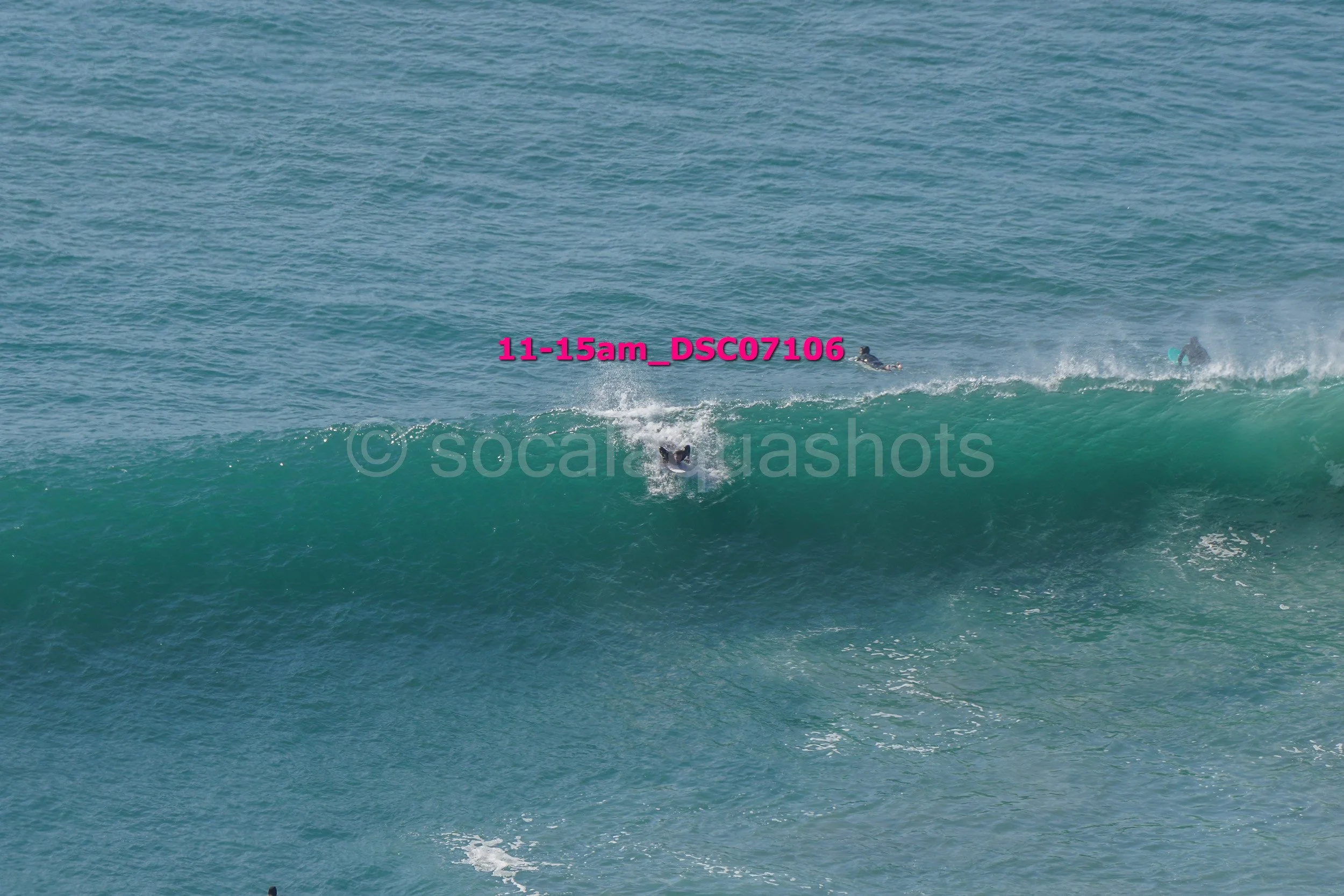Surfers riding a wave in the ocean during daytime.