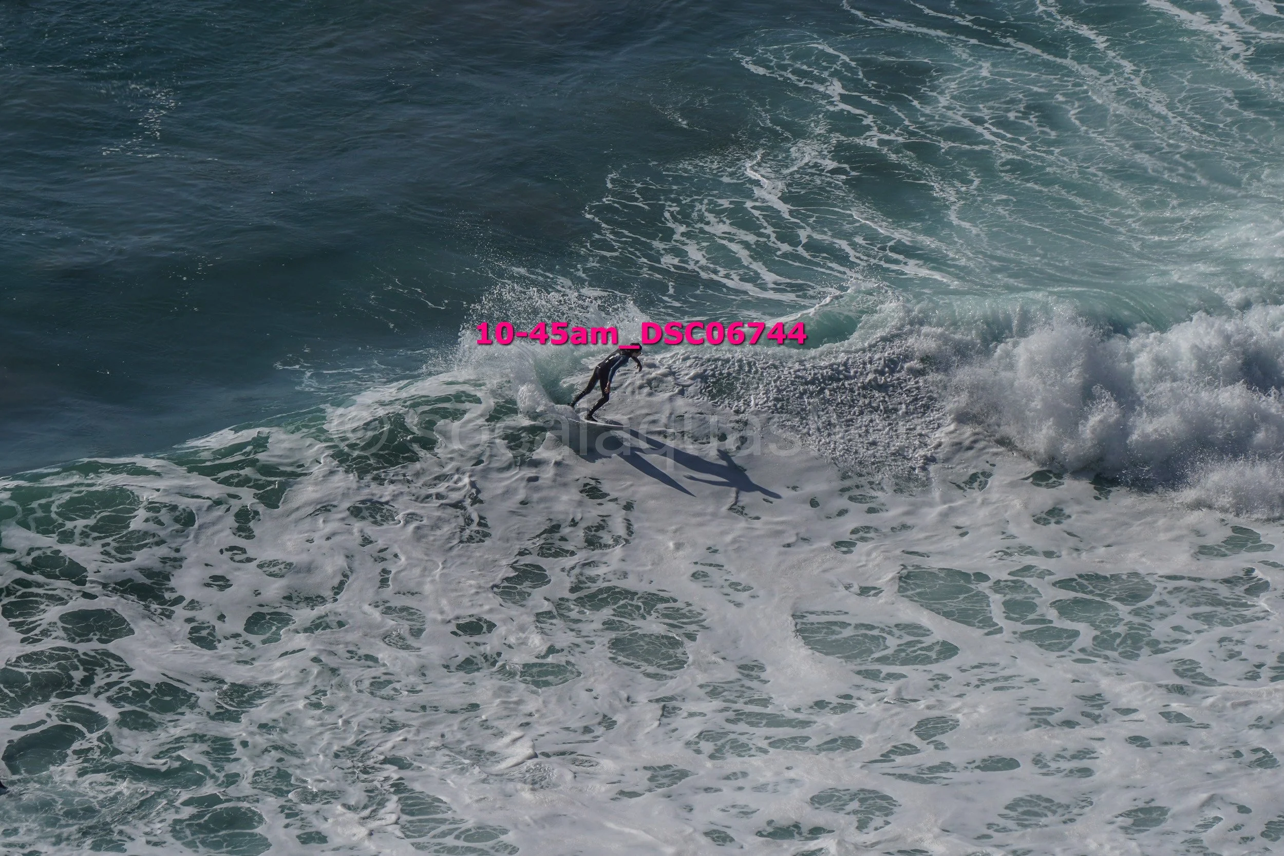 A person surfing on a large wave in the ocean.