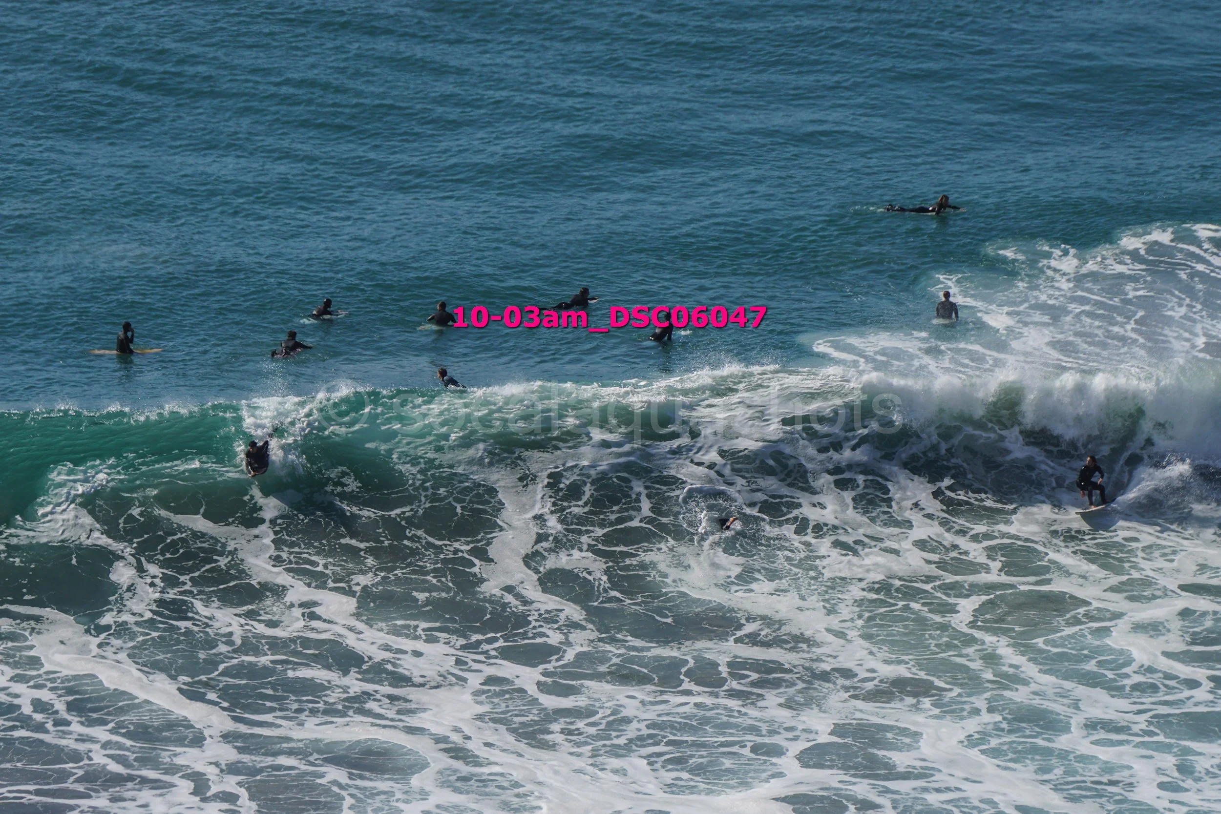 A group of people surfing in turbulent ocean waters with waves crashing.