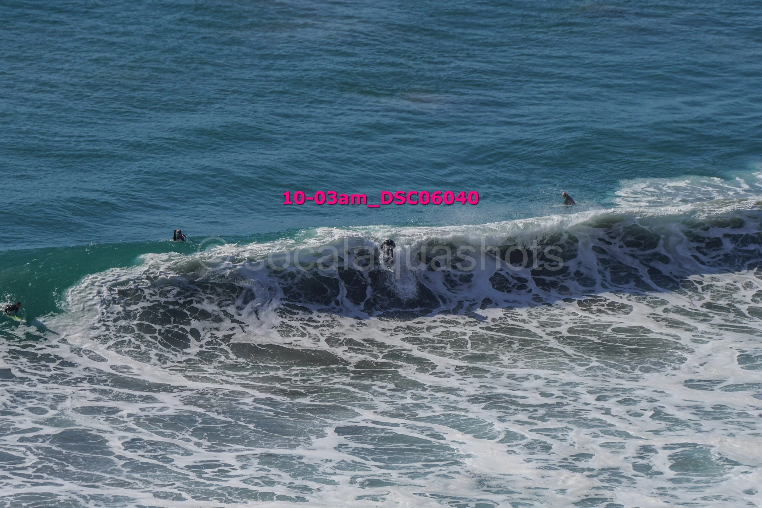 Surfers riding waves in the ocean near the shoreline during daytime.