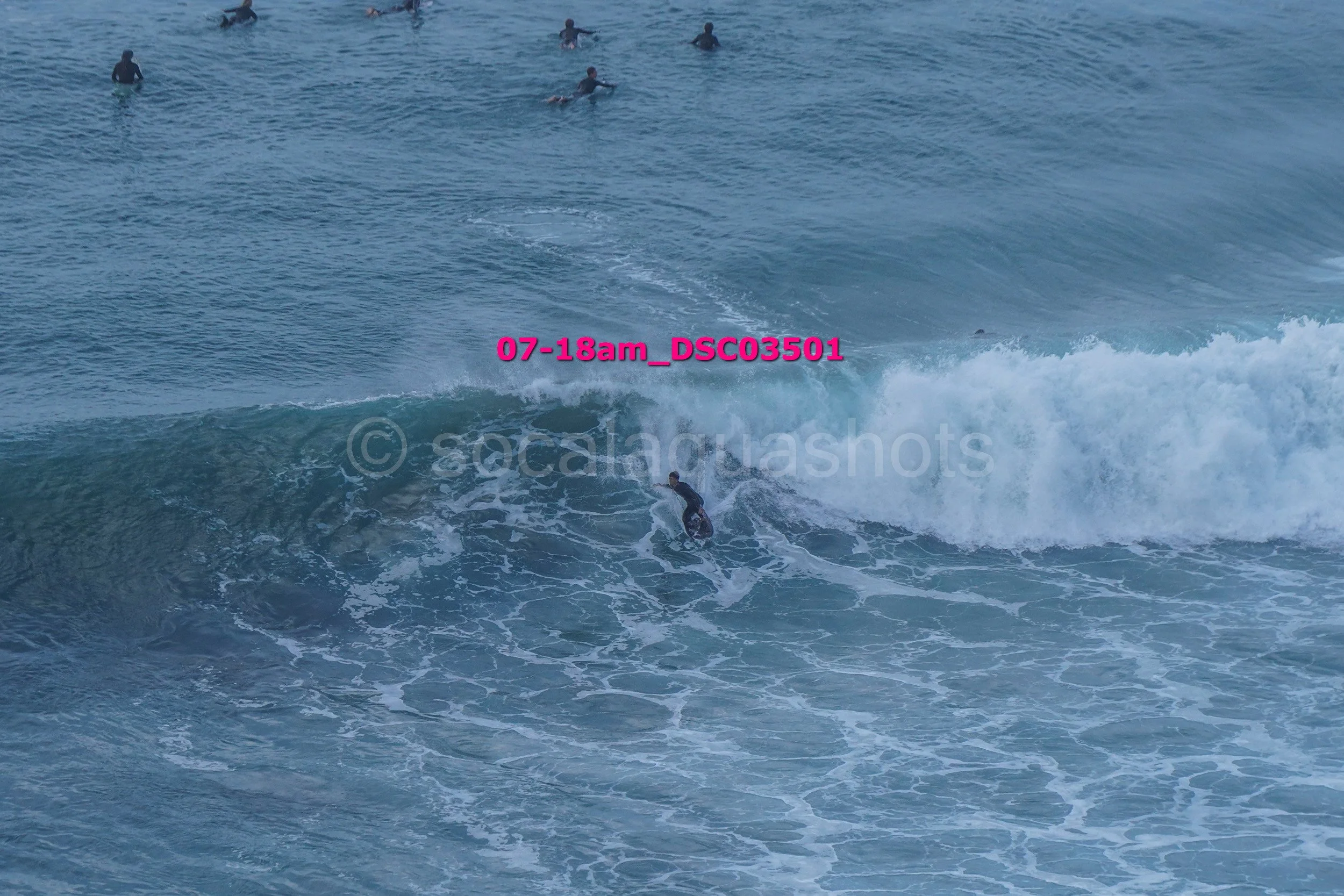 A person surfing a wave in the ocean with several other surfers in the background.