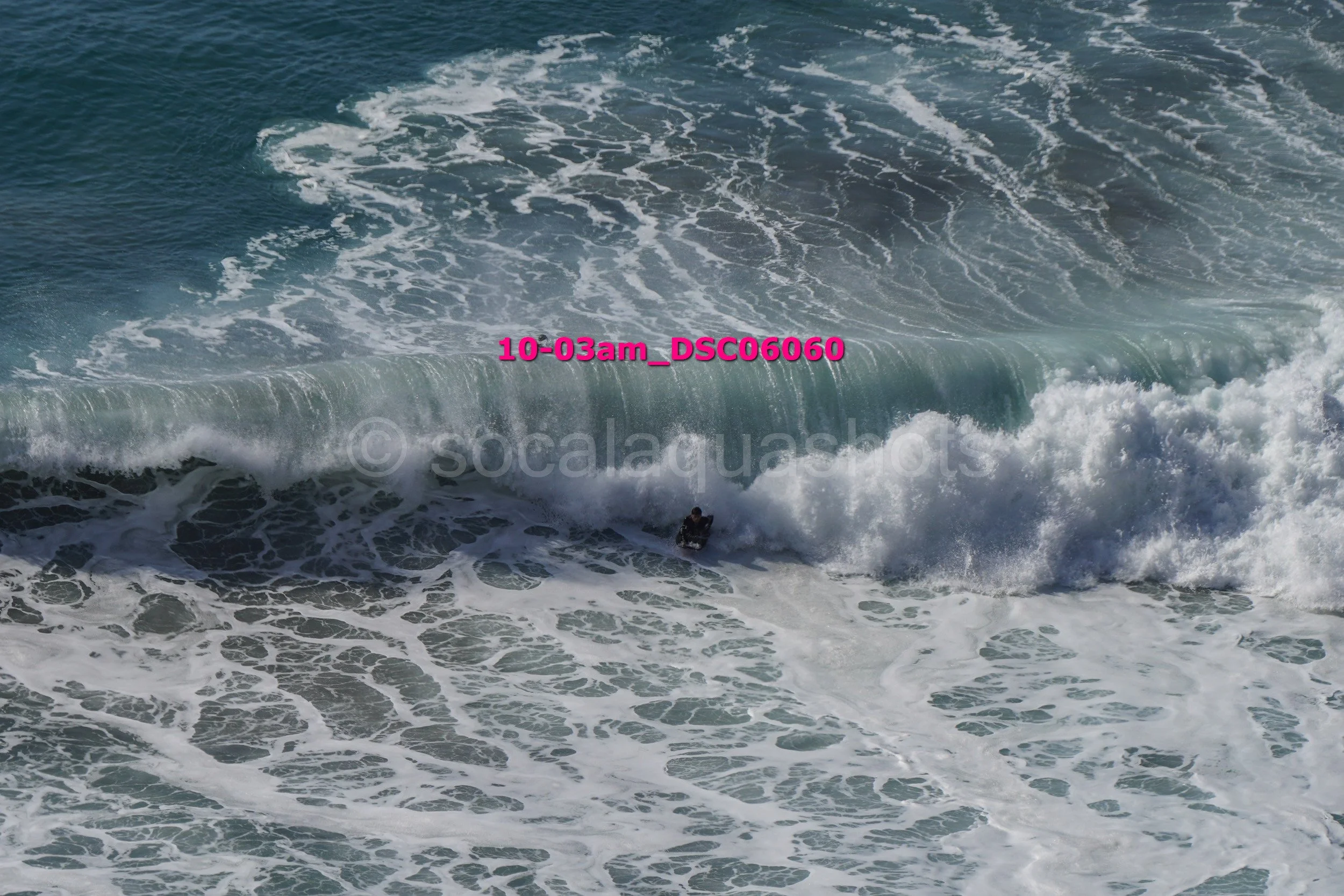 A person surfing on a large ocean wave during daytime.