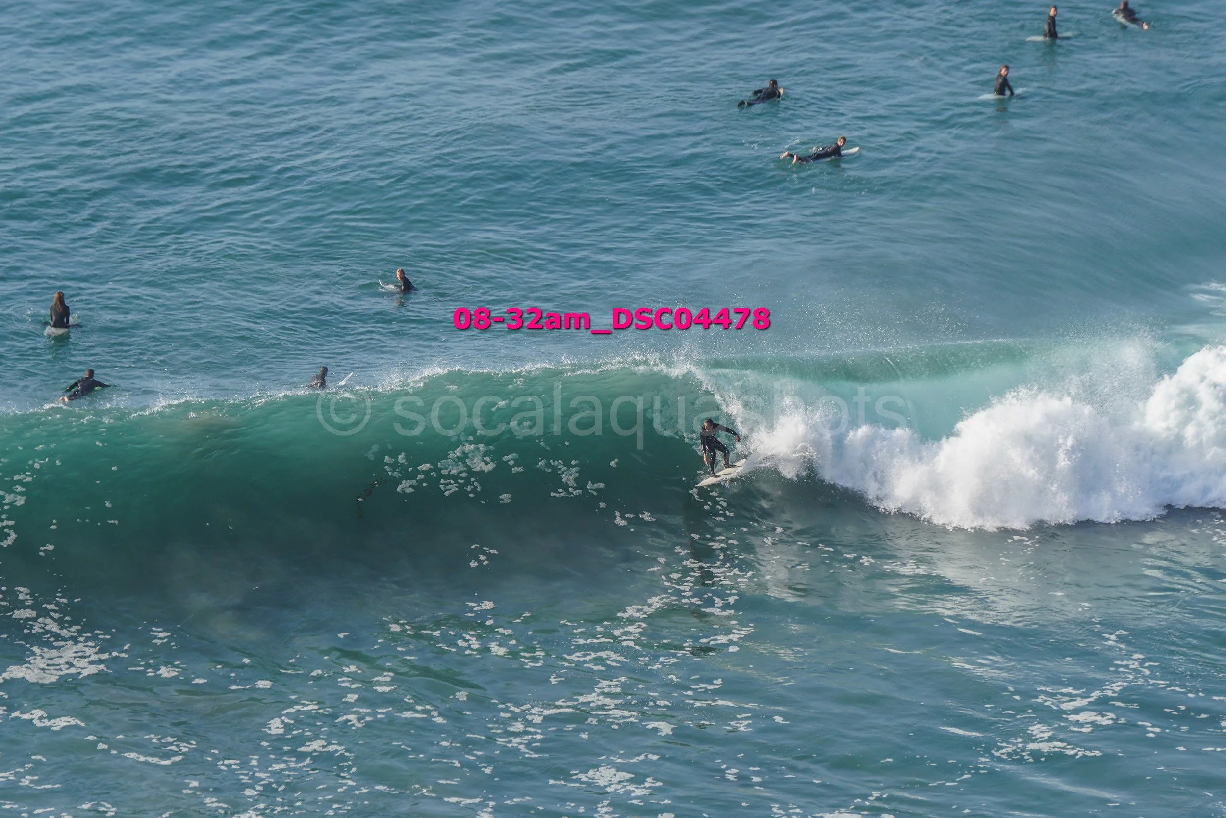 A surfer riding a wave while multiple surfers are in the water nearby.