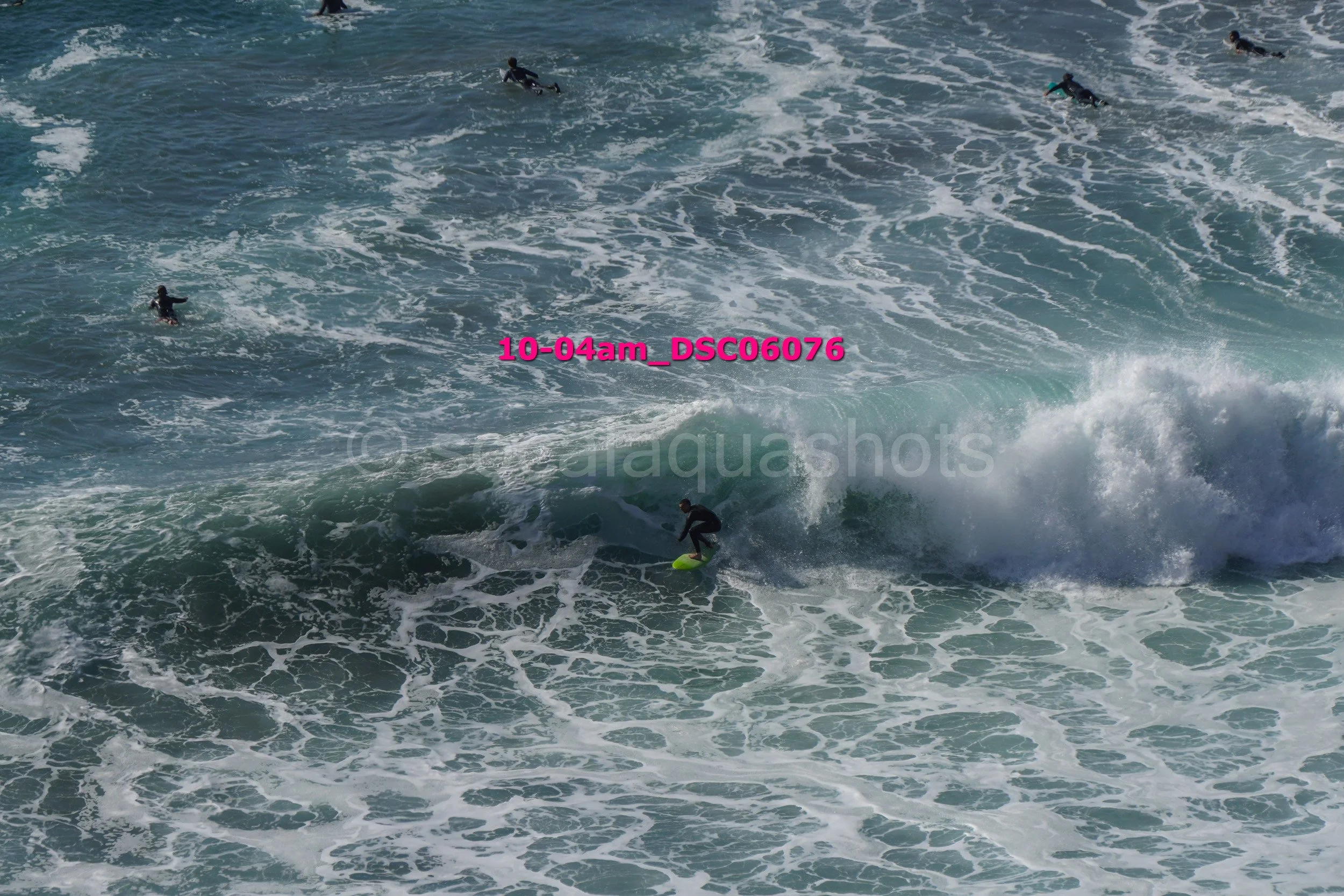 Surfer riding a wave while other surfers are visible in the water.