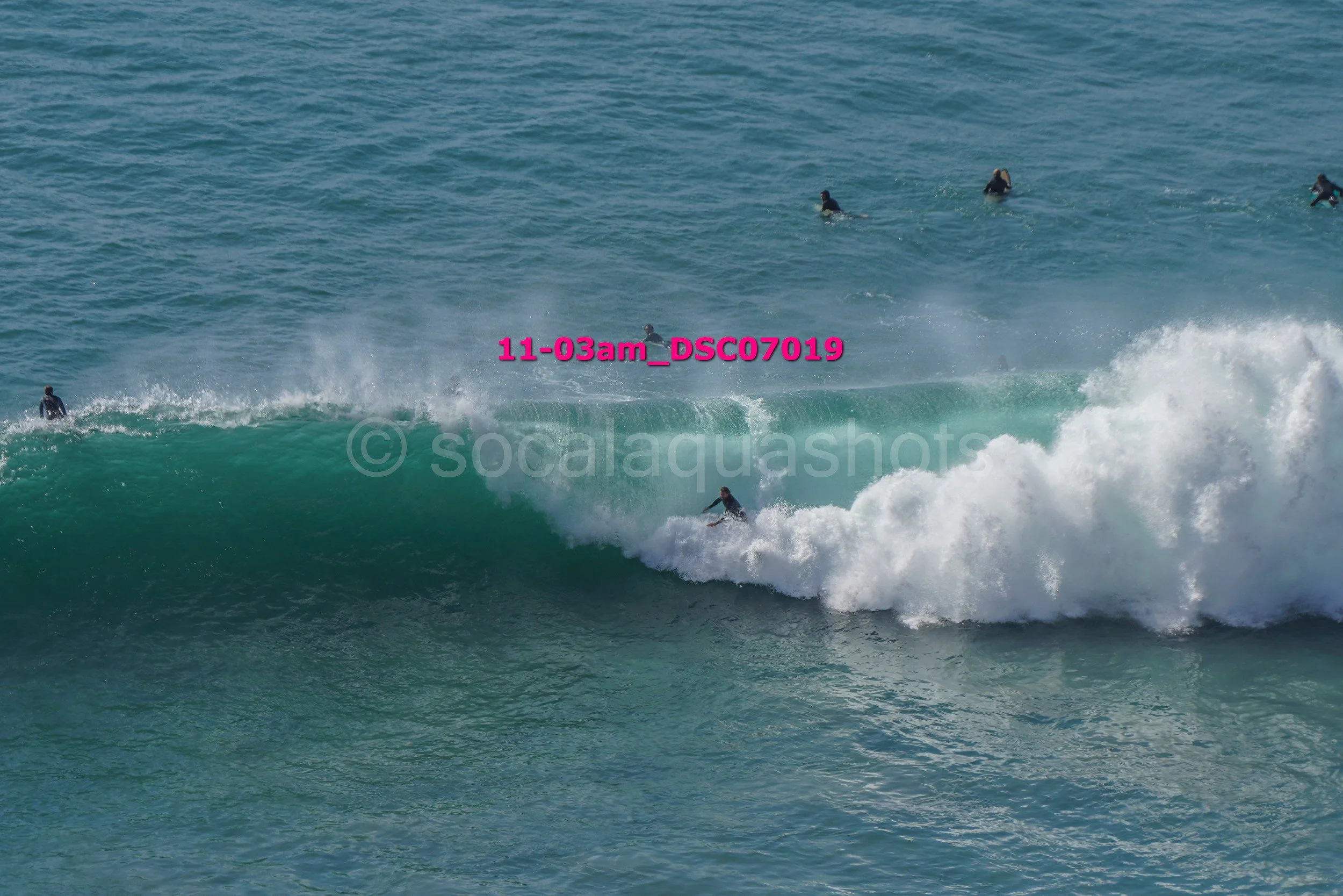 Surfer riding a wave with several surfers in the water around him.