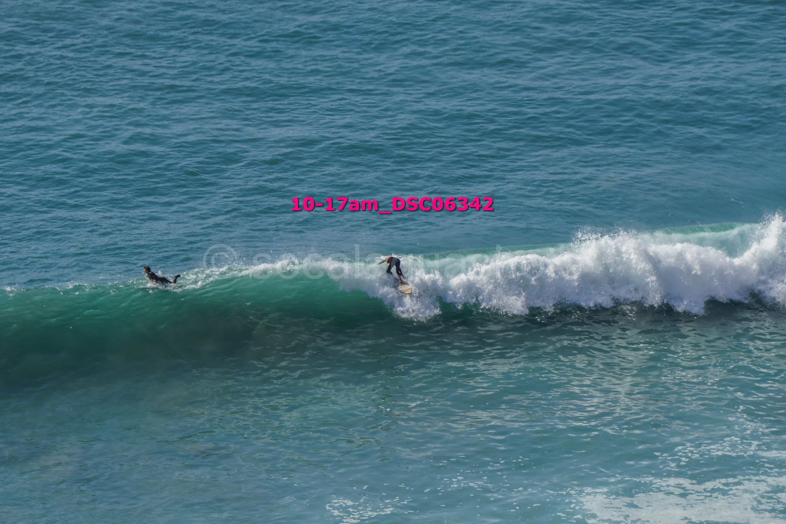 Surfer riding a wave on the ocean, with another surfer in the water nearby.