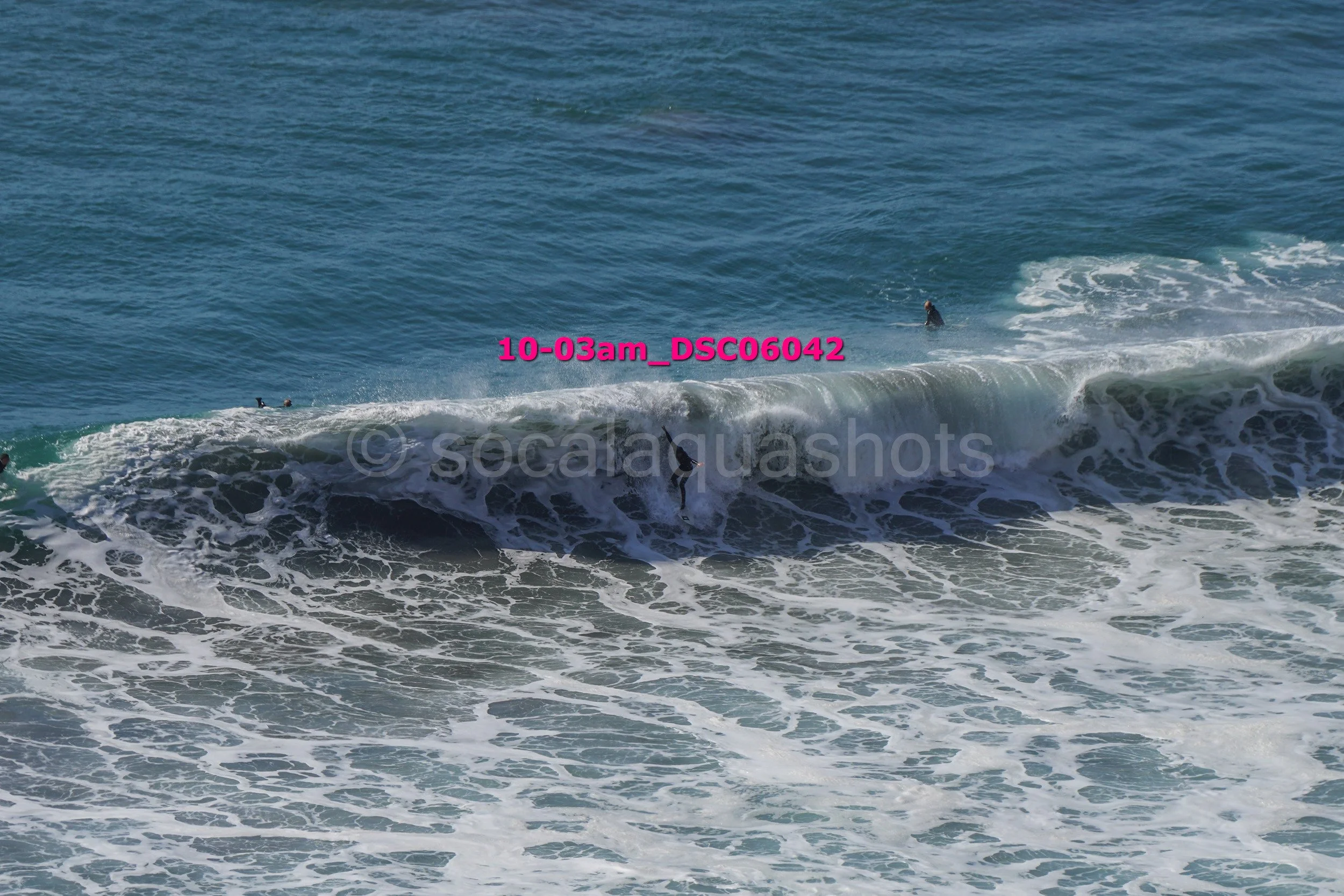 People surfing on ocean waves with some surfers visible in the water