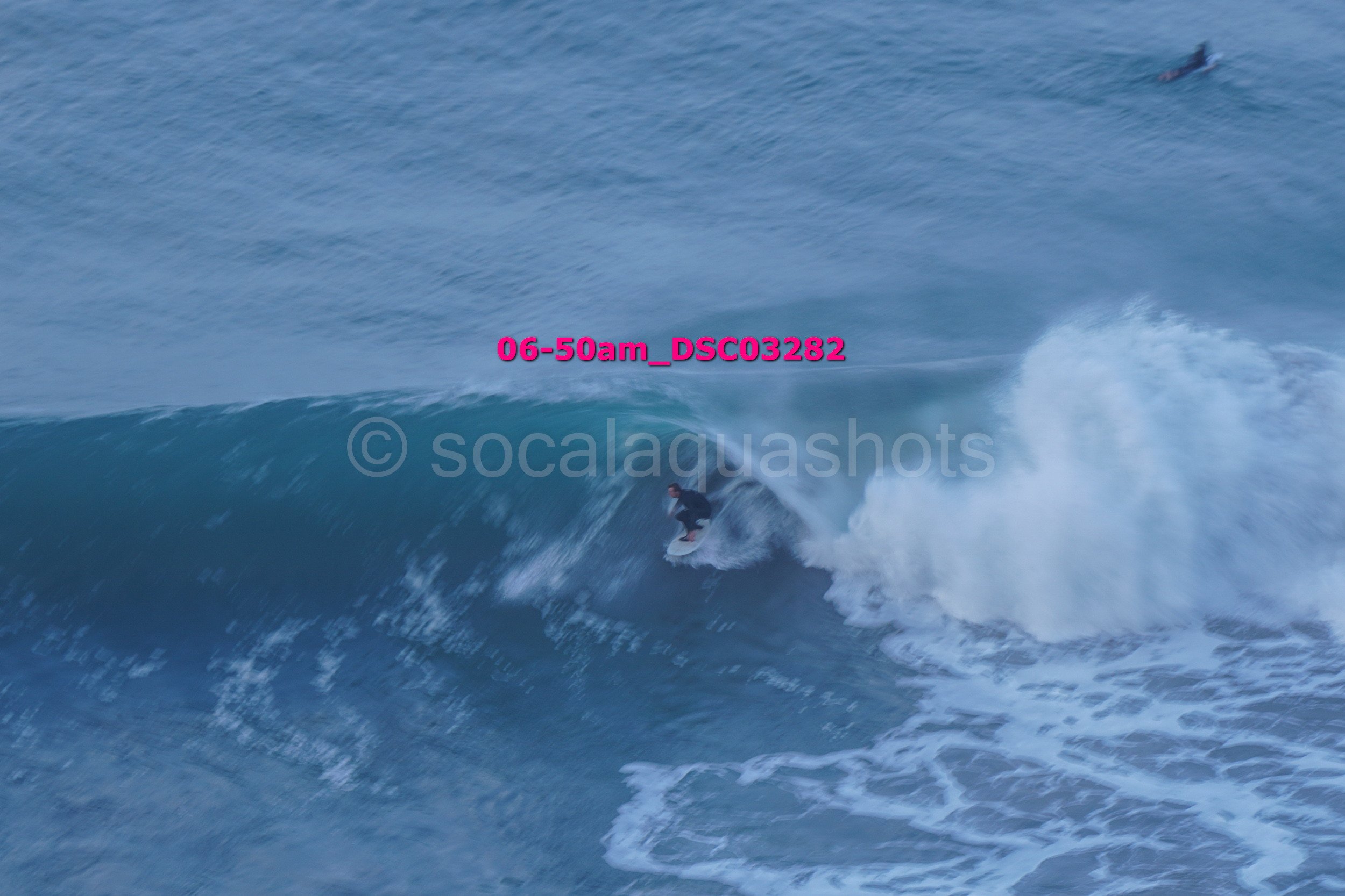 A person surfing on a wave in the ocean during early morning.