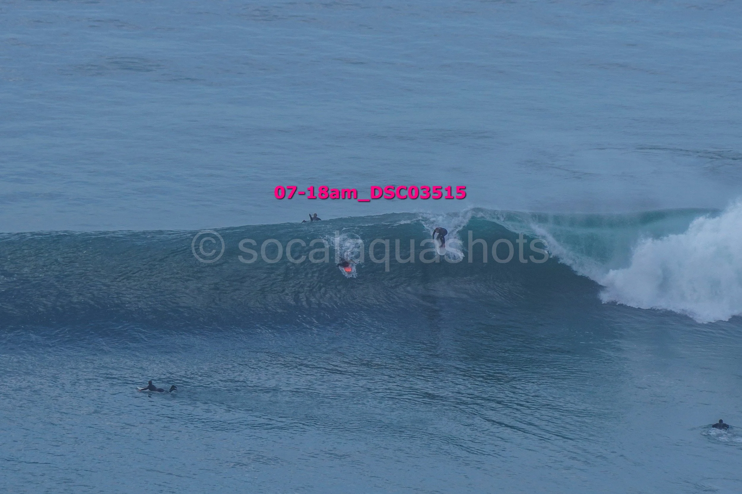Multiple surfers riding and waiting for waves in the ocean.