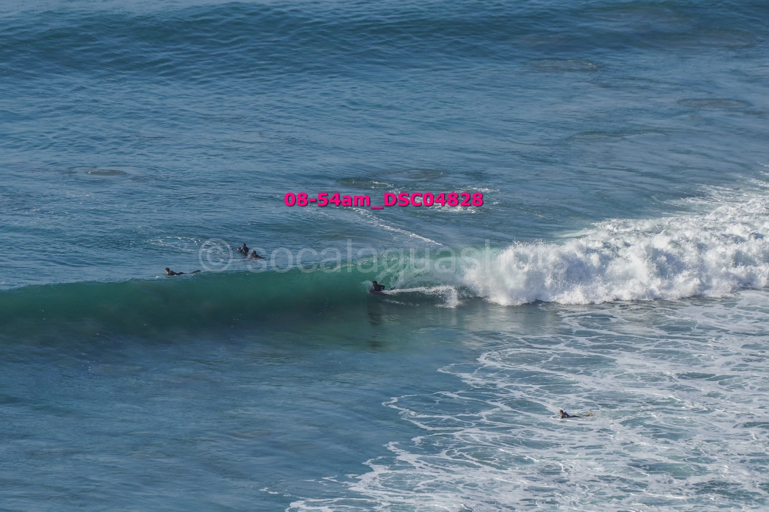 Surfers riding and waiting on ocean waves at the beach.
