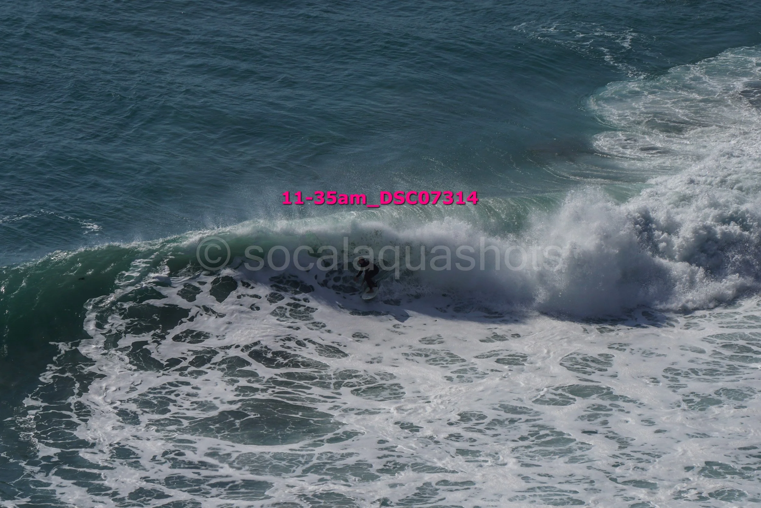 A surfer riding a wave in the ocean with white foam and turbulent water.