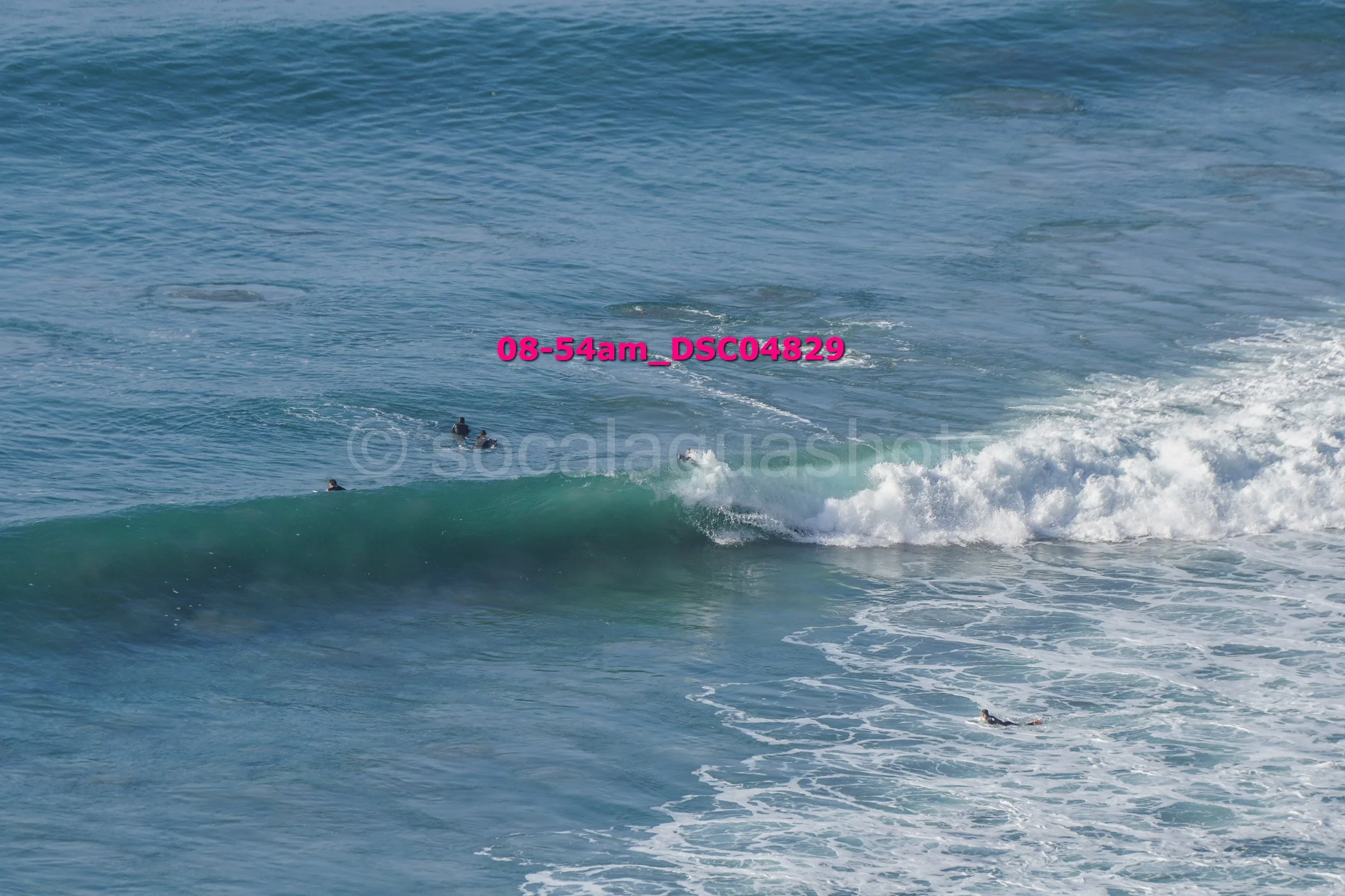 People surfing in the ocean with breaking waves and visible water spray.