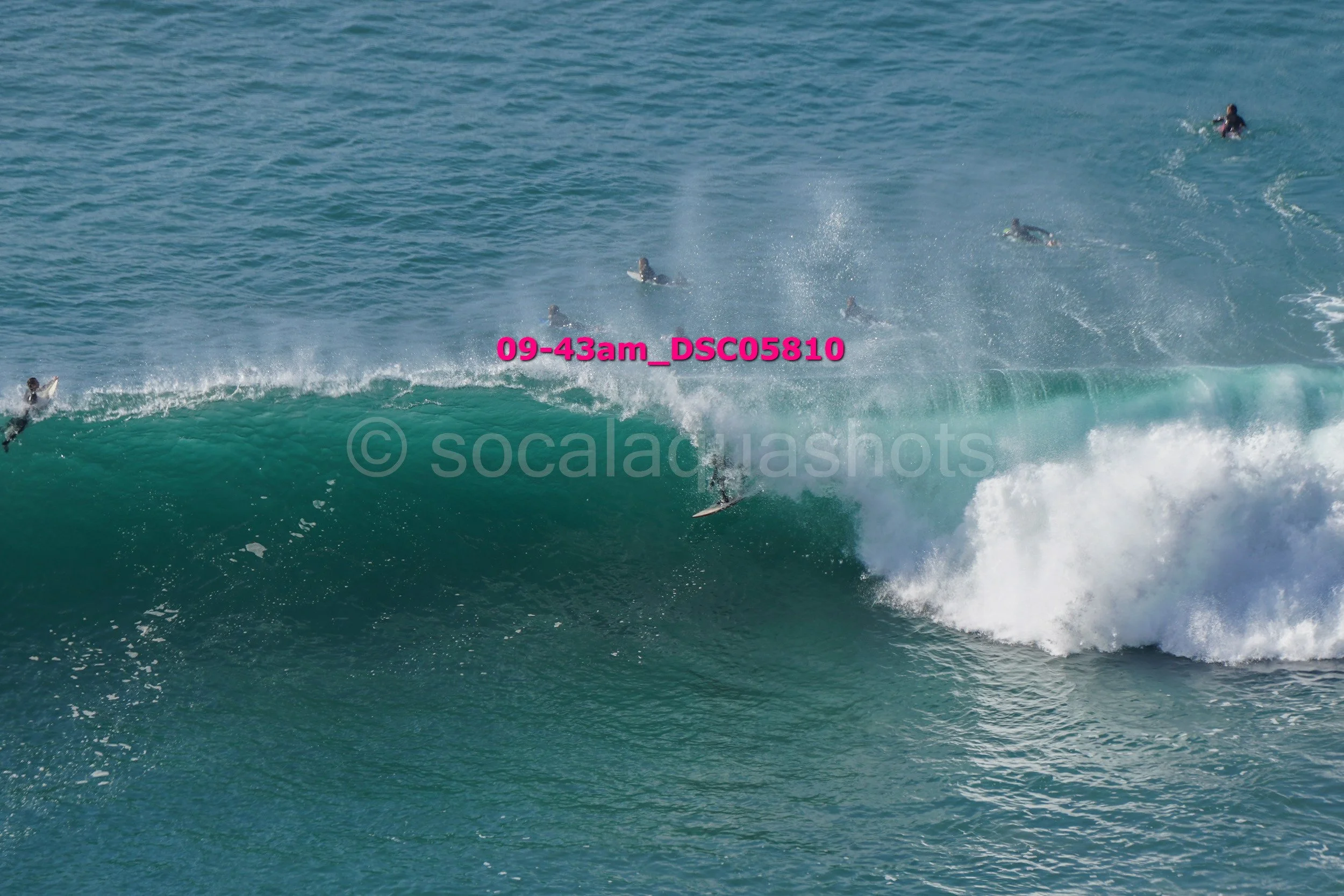 Multiple surfers riding and navigating large ocean waves in the sea.