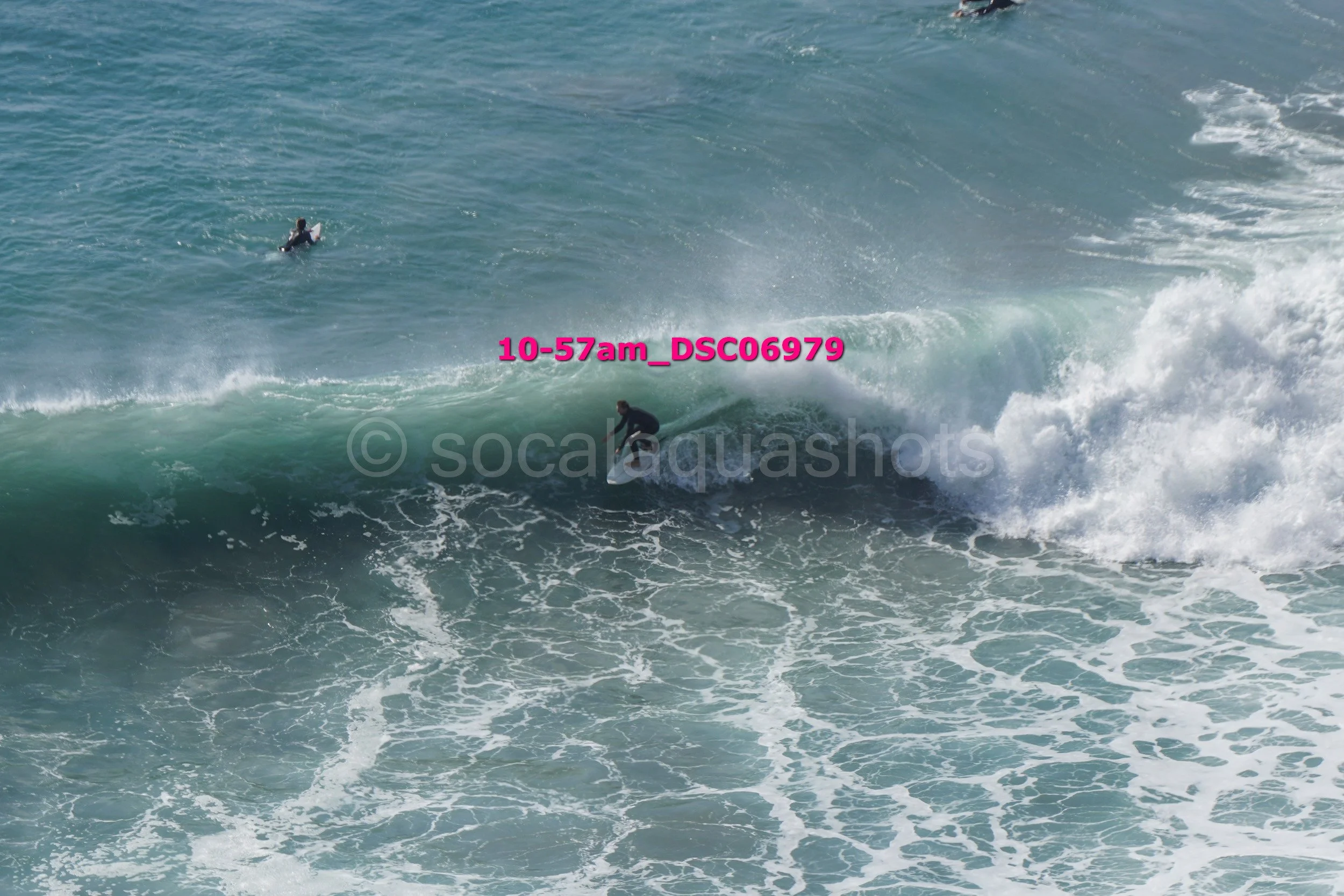 A person surfing on a wave with an additional surfer in the background in the ocean