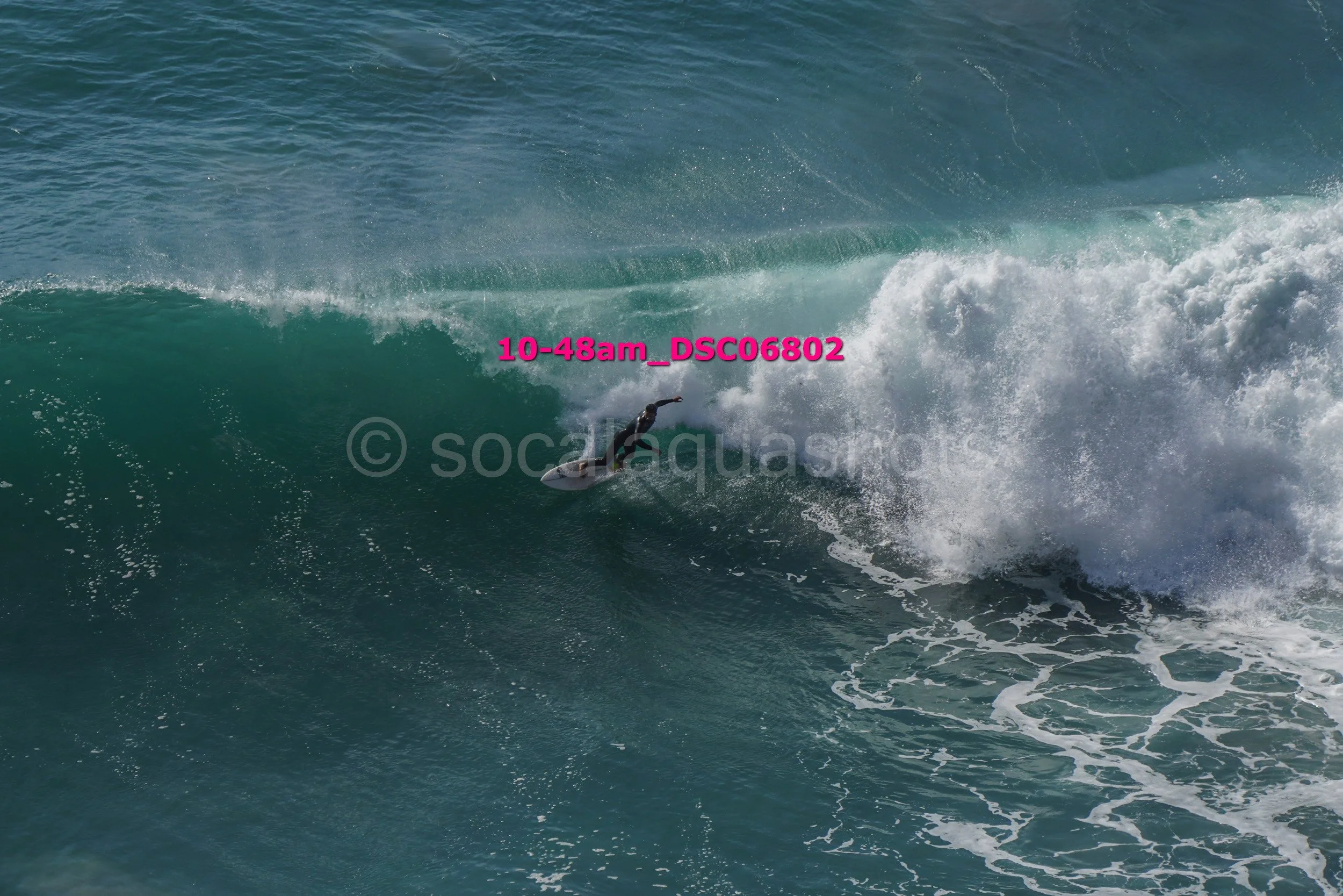 A surfer riding a large wave in the ocean, with spray and foam around them.